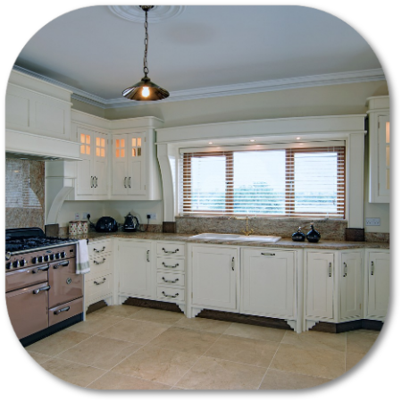 Cream-colored kitchen with a pink stove, cabinets, large window with blinds, and pendant light.
