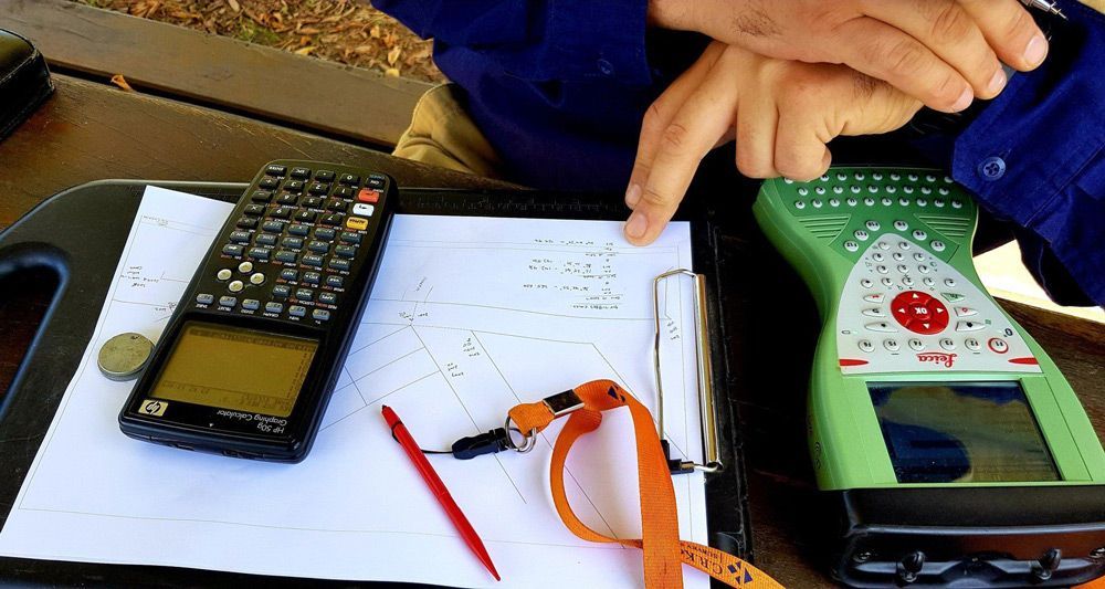 Worker Doing Some Calculations on Clipboard Using Calculator — Surveyor In Canowindra, NSW
