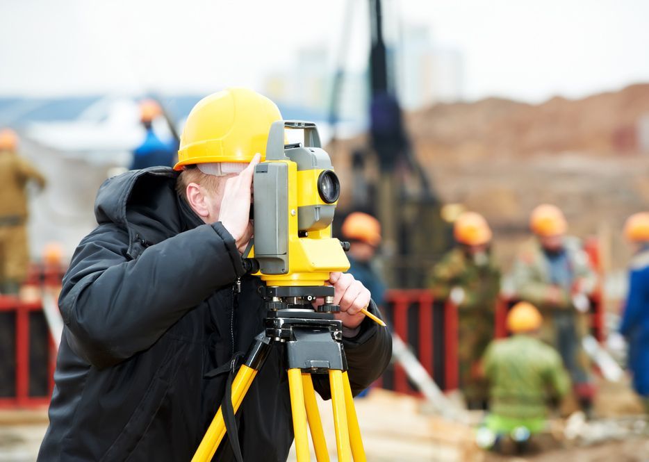 Man Wearing A Yellow Hard Hat Looks Through A Telescope — Surveyor In Forbes, NSW