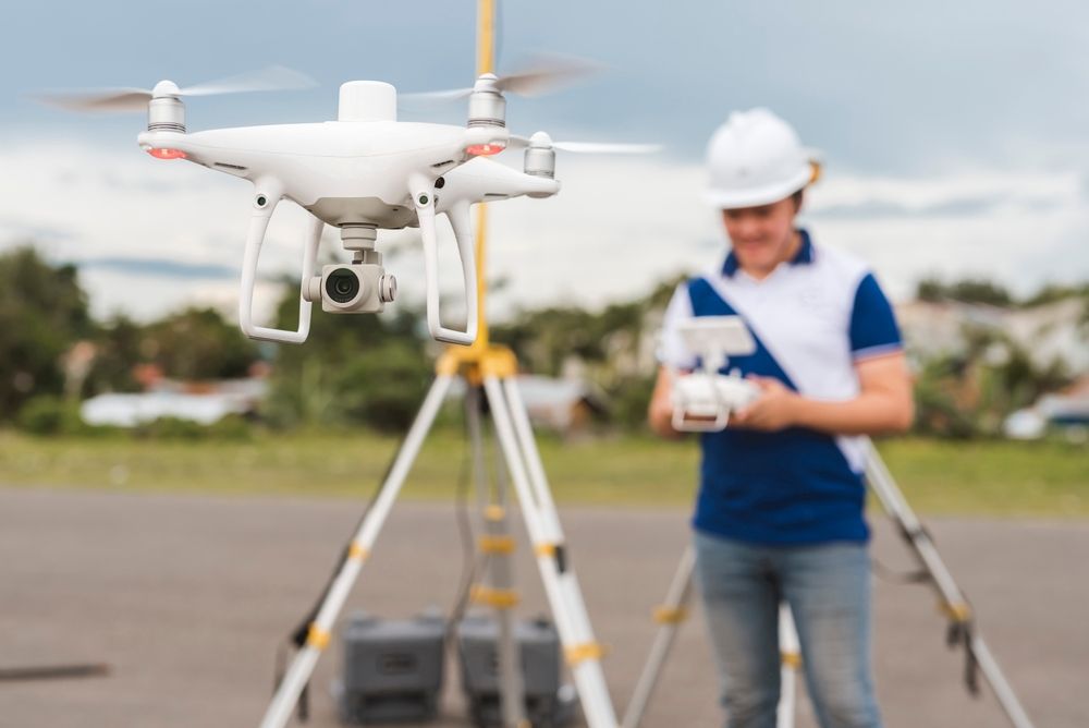 Man Is Holding A Remote Control In Front Of A Drone — Surveyor In Condobolin, NSW