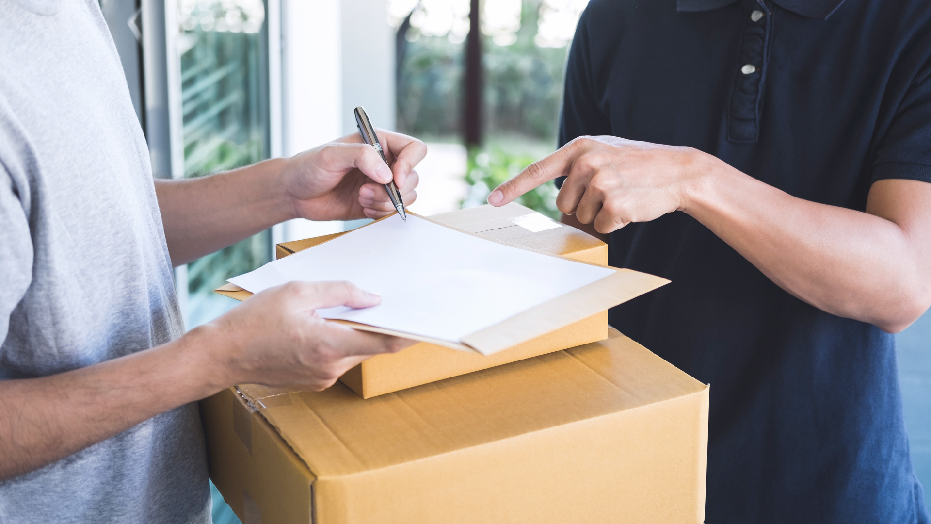 A man is signing a piece of paper next to a cardboard box.
