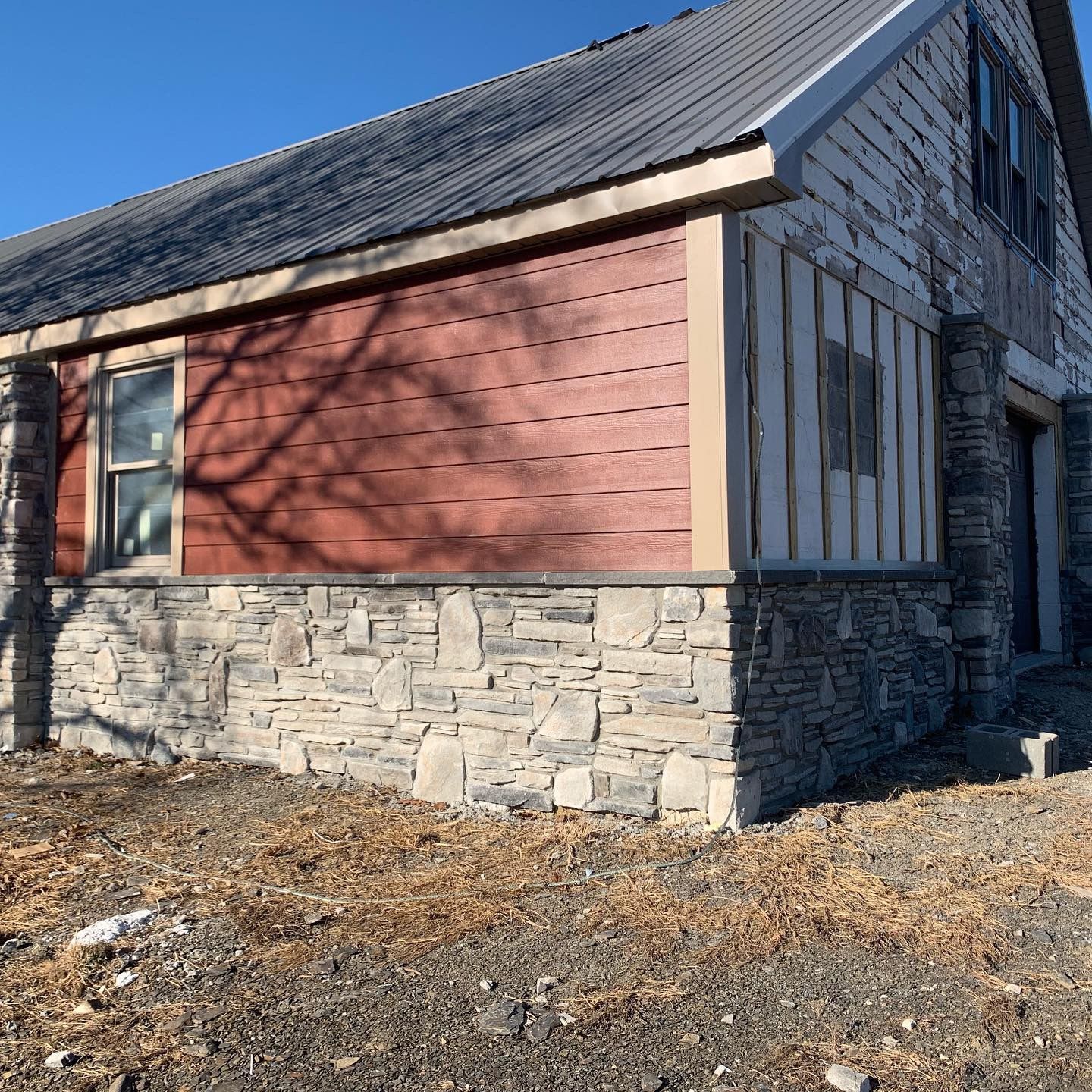 A house with a red siding and a stone wall
