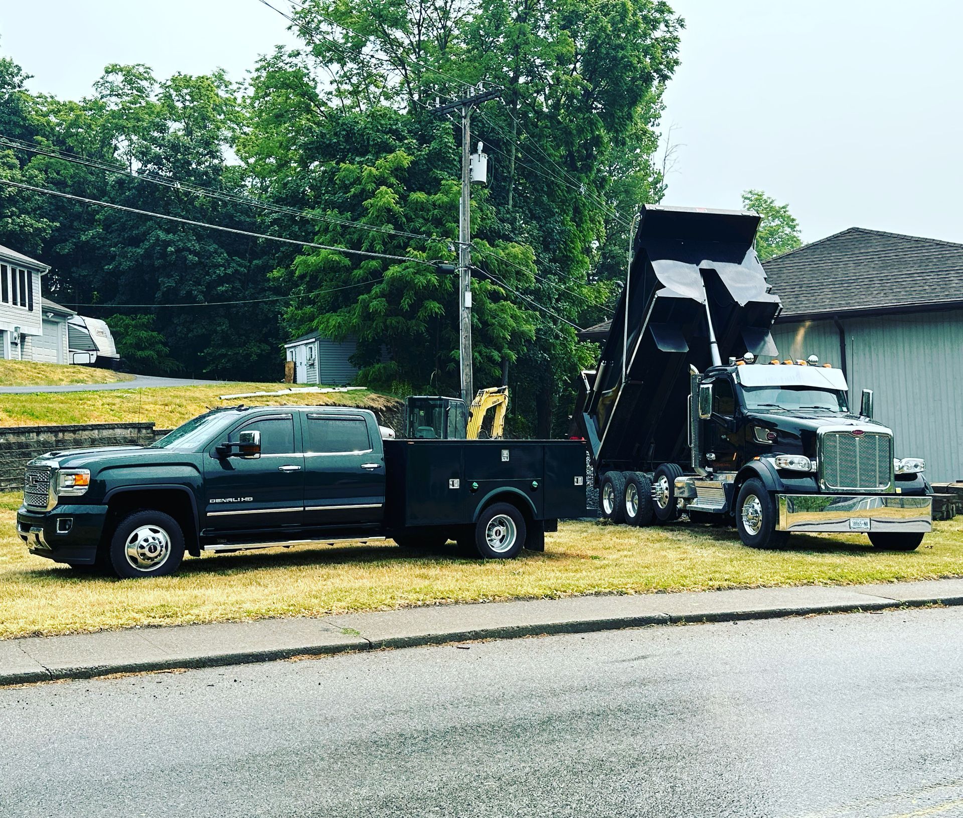 Two dump trucks are parked next to each other on the side of the road.