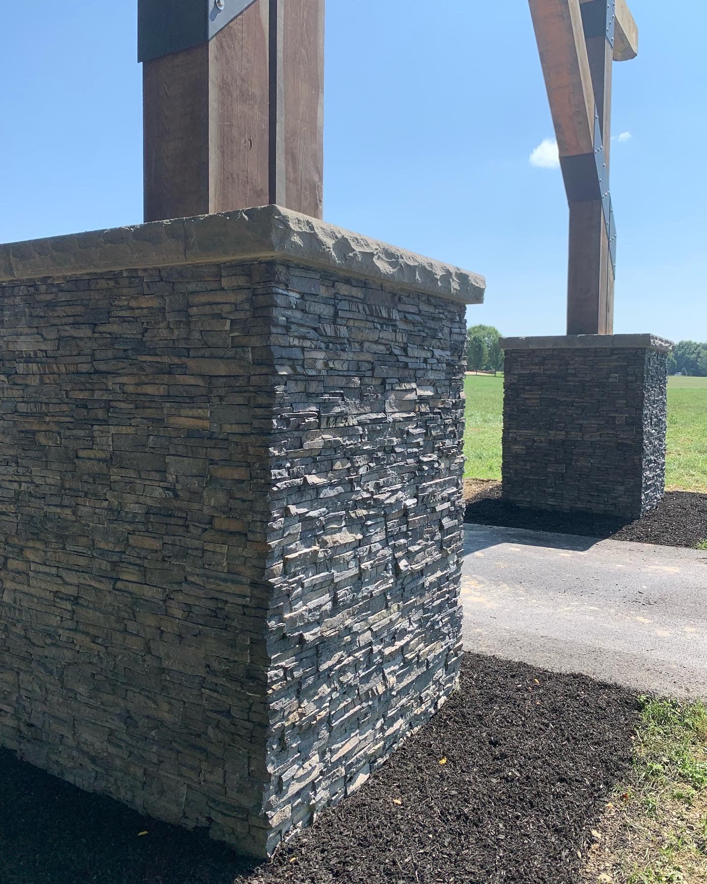 A stone wall with a wooden cross in the background.
