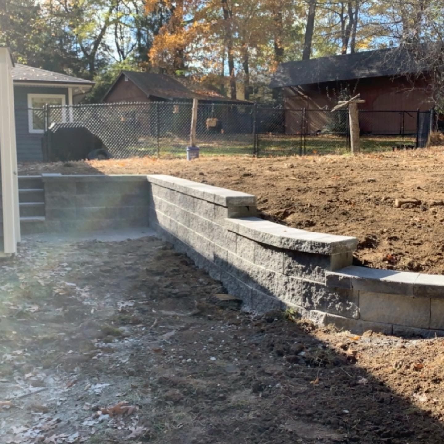 A brick wall is being built in the backyard of a house.
