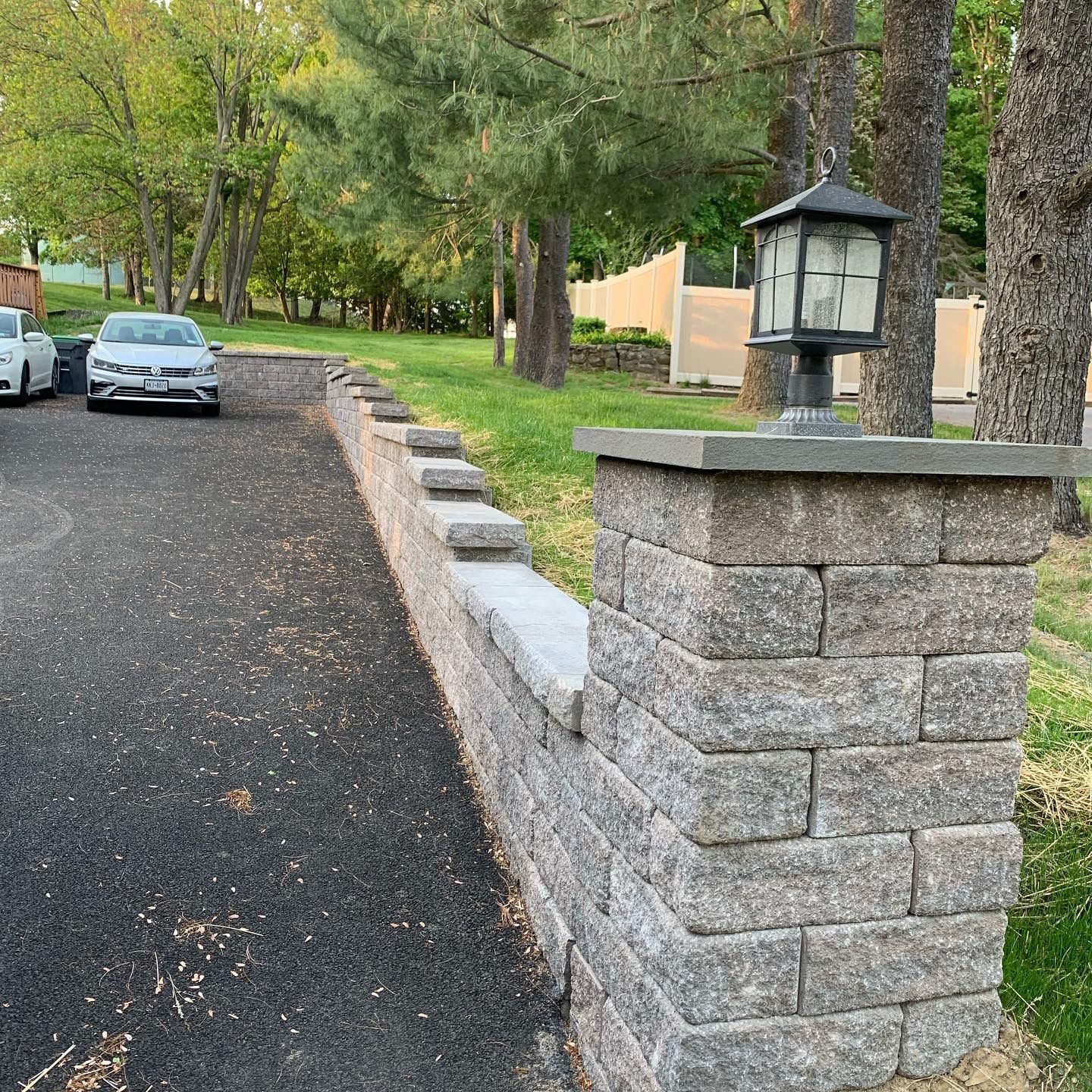 A car is parked on the side of the road next to a stone wall.