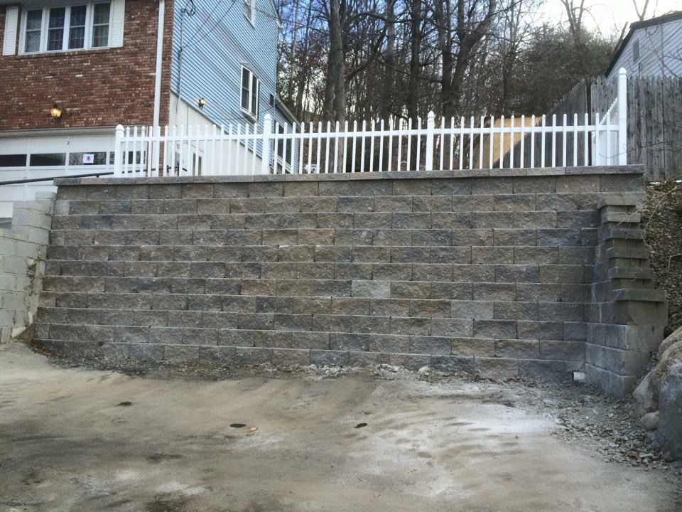 A brick wall with a white picket fence behind it