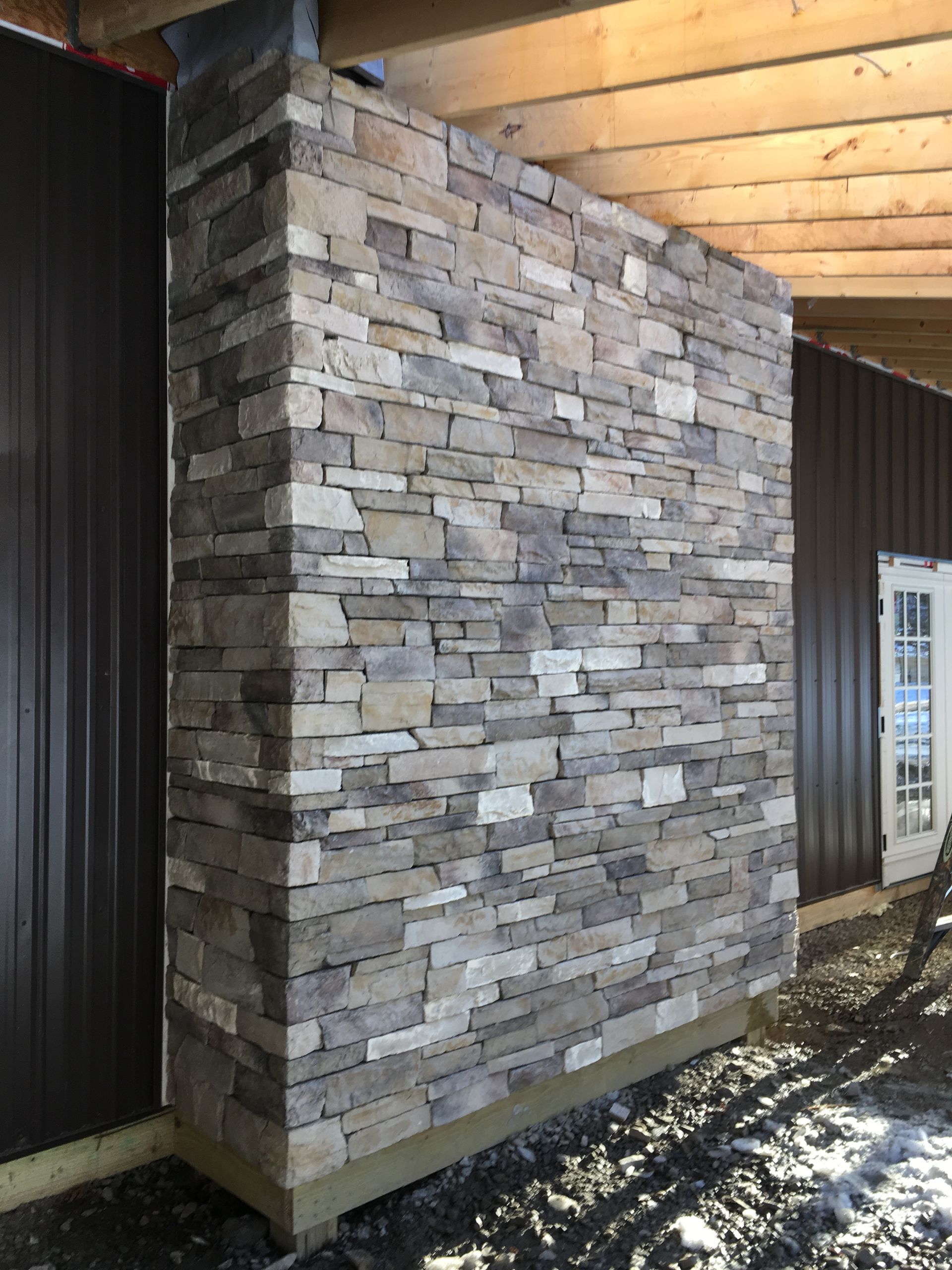 A large stone wall is sitting next to a building.