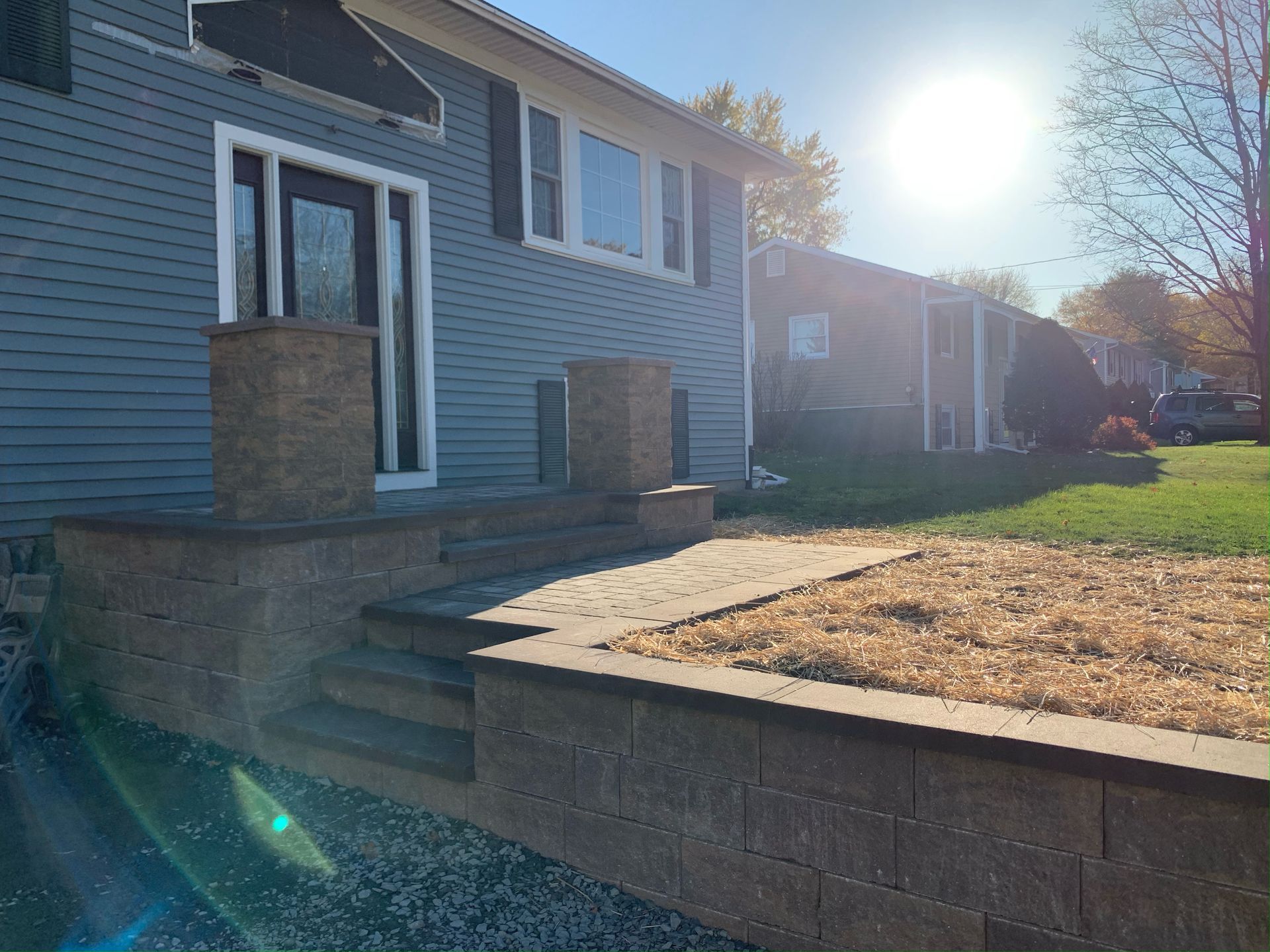 A house with a brick wall and stairs in front of it.