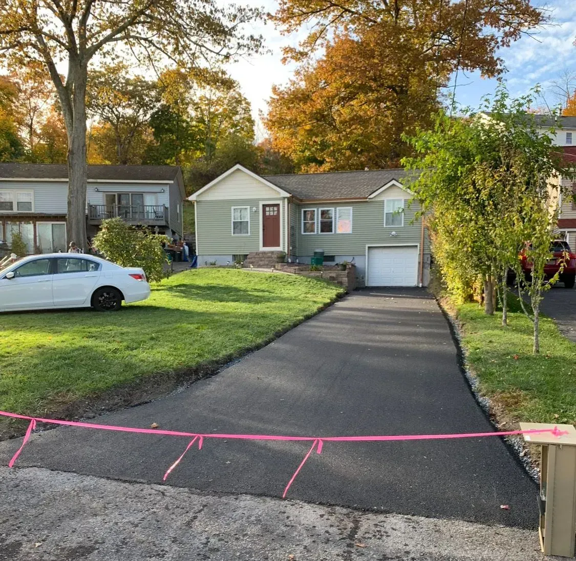 A white car is parked in front of a house.