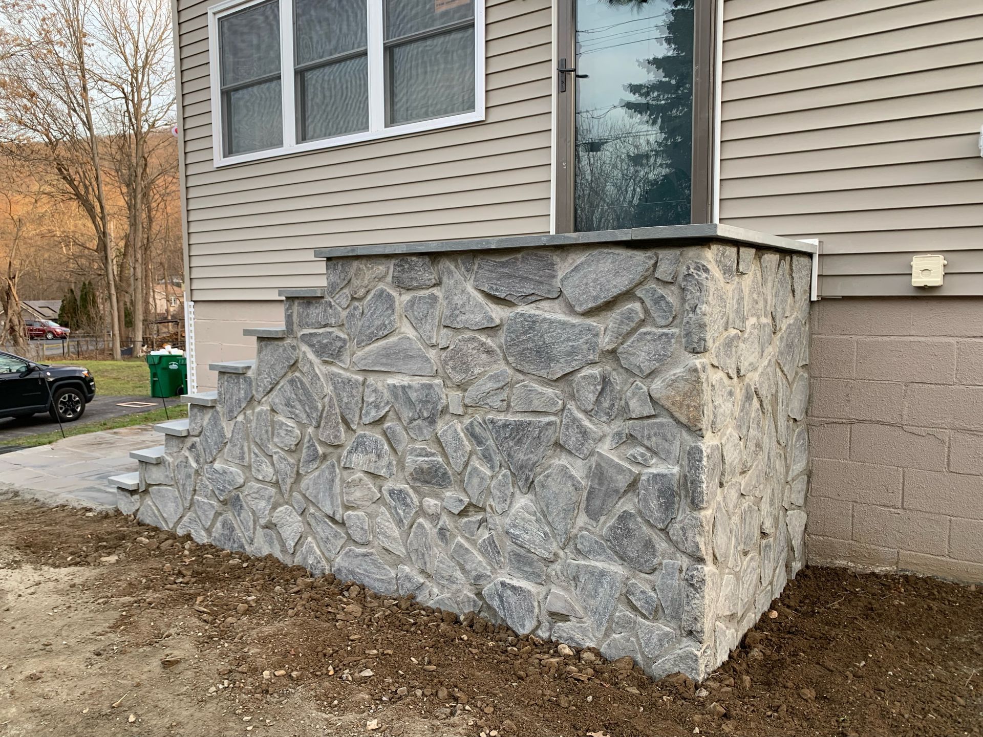 A stone wall with stairs leading up to the front door of a house.