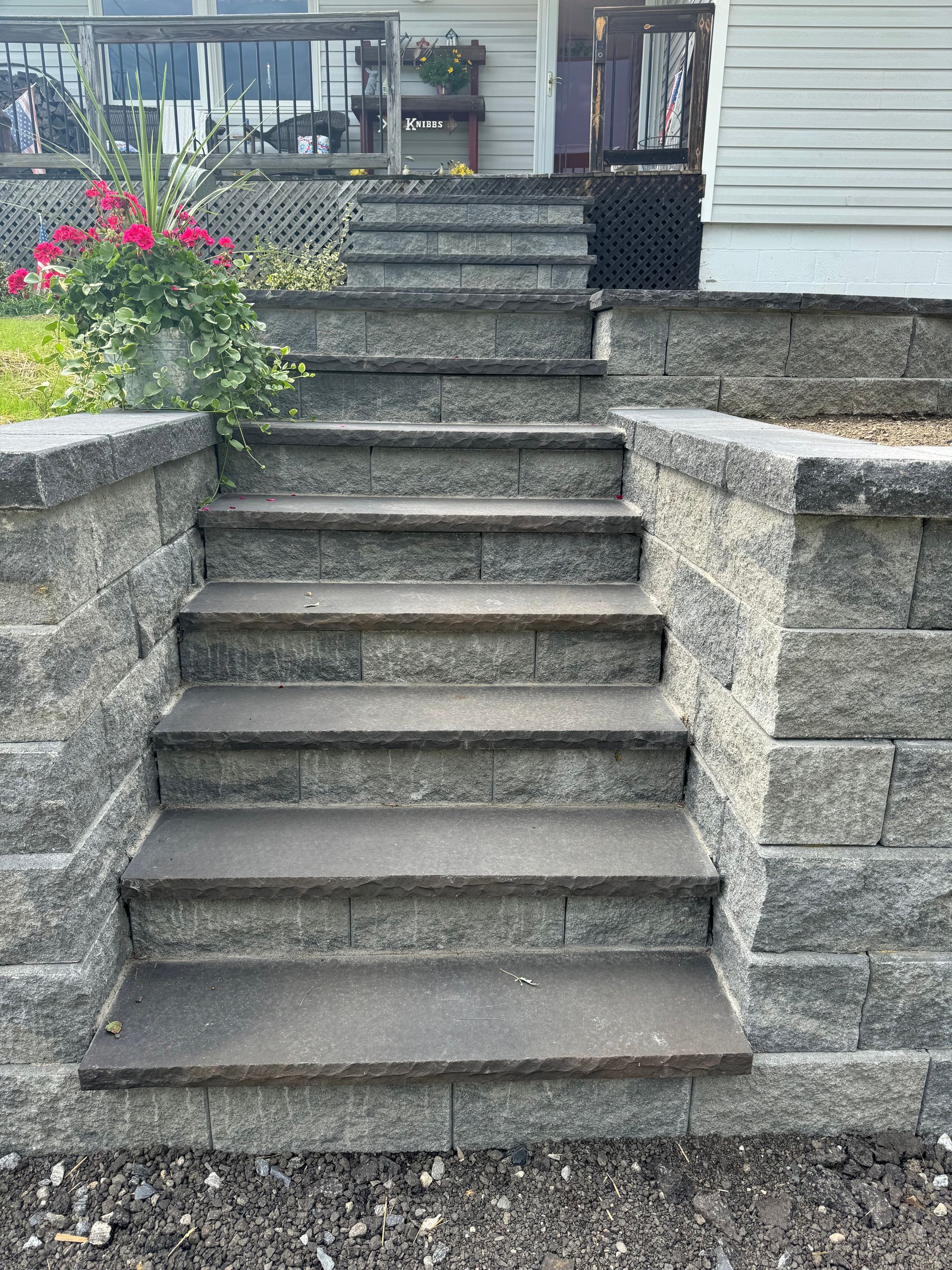 A set of stairs leading up to a house next to a stone wall.