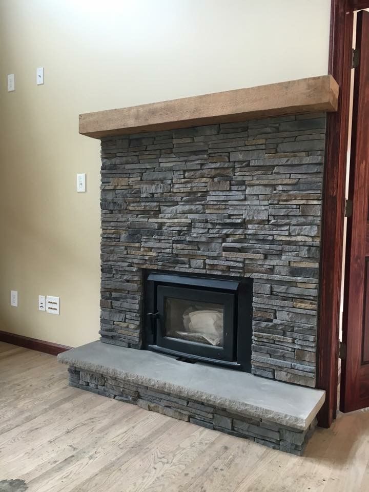 A stone fireplace with a wooden mantle in a living room