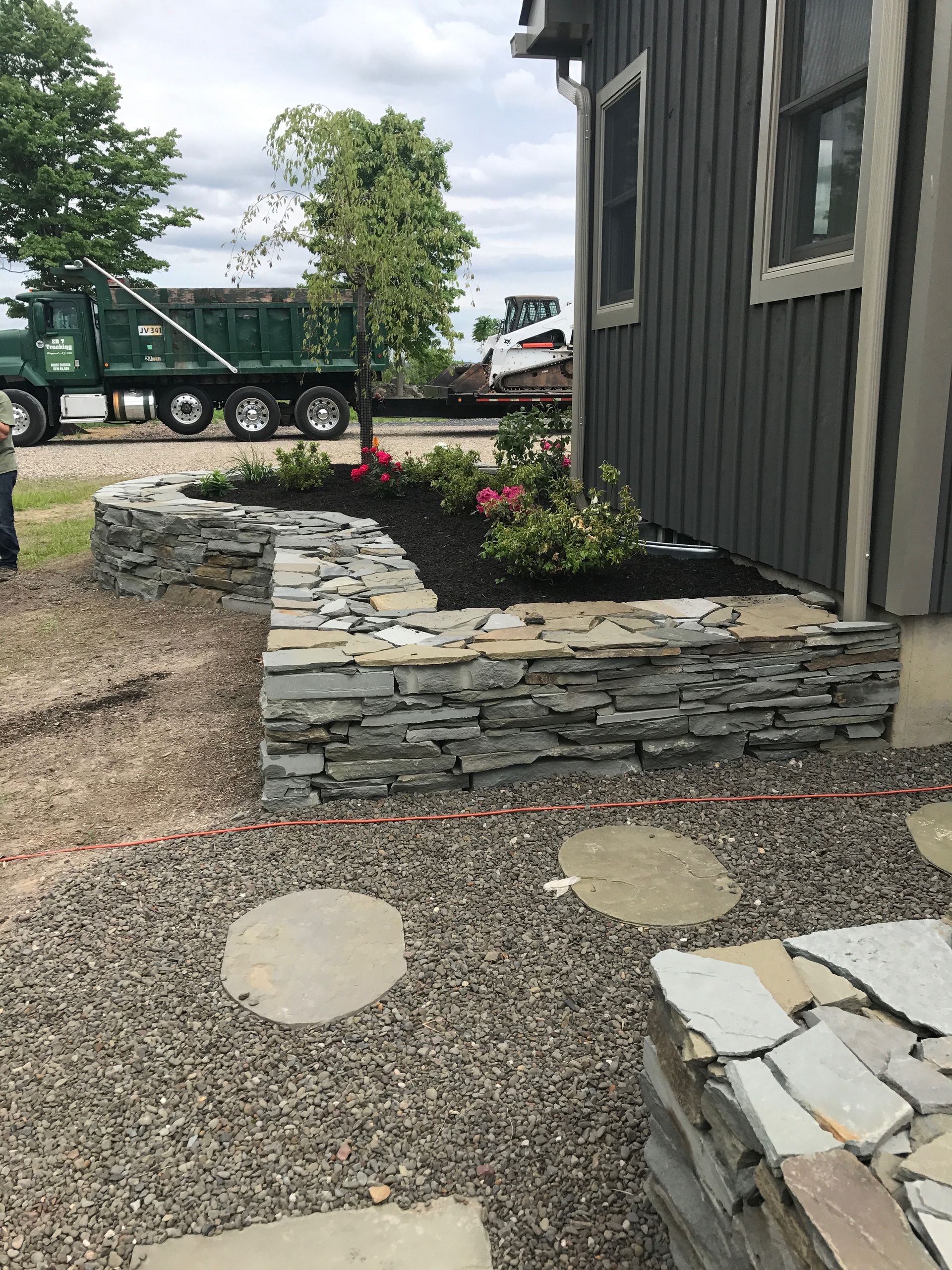 A stone wall is being built in front of a house.
