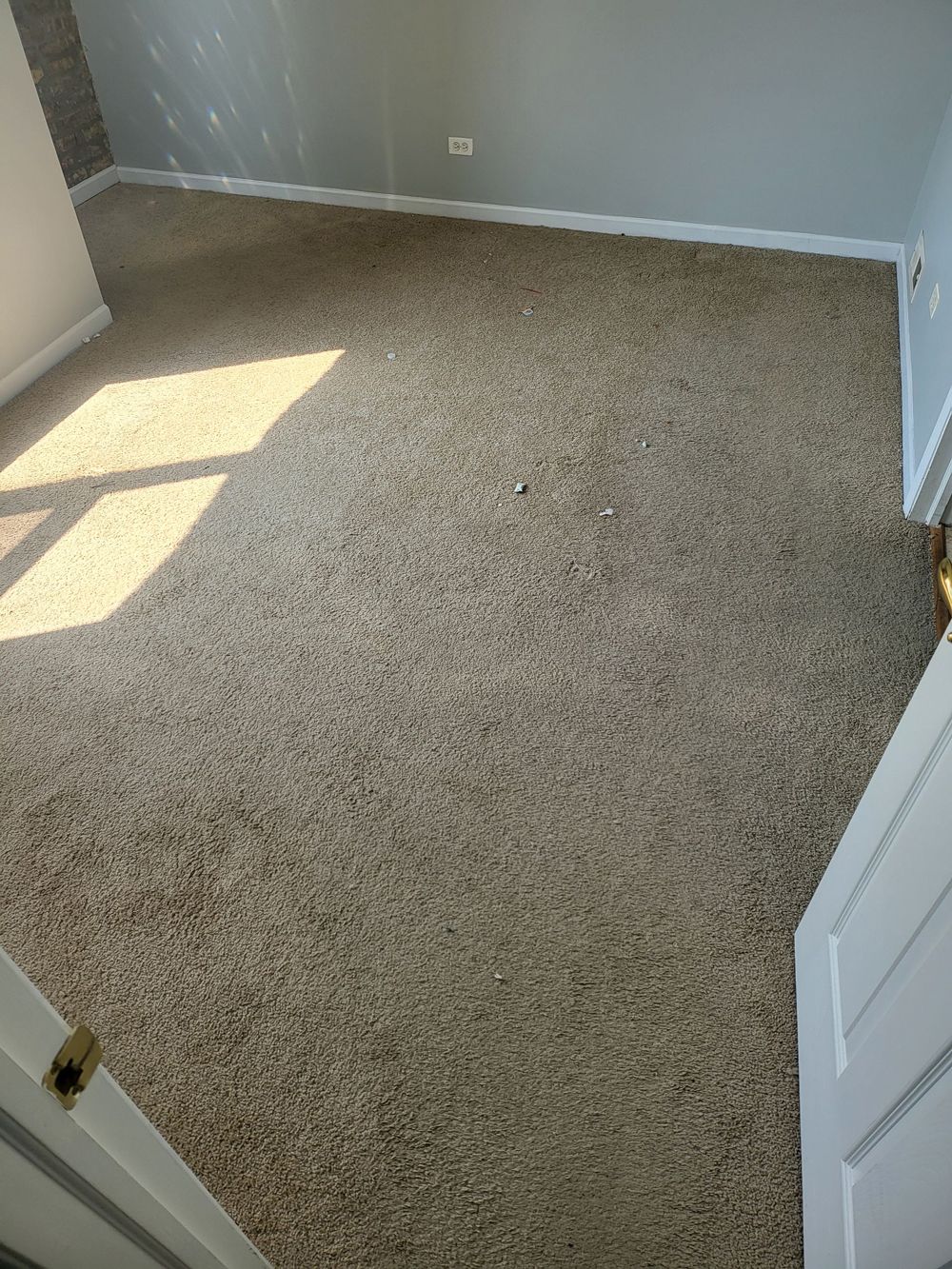 Before image of a room with a carpeted floor and a door