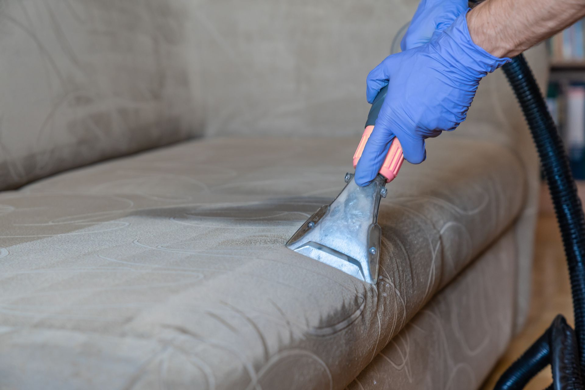 a person is cleaning a couch with a vacuum cleaner