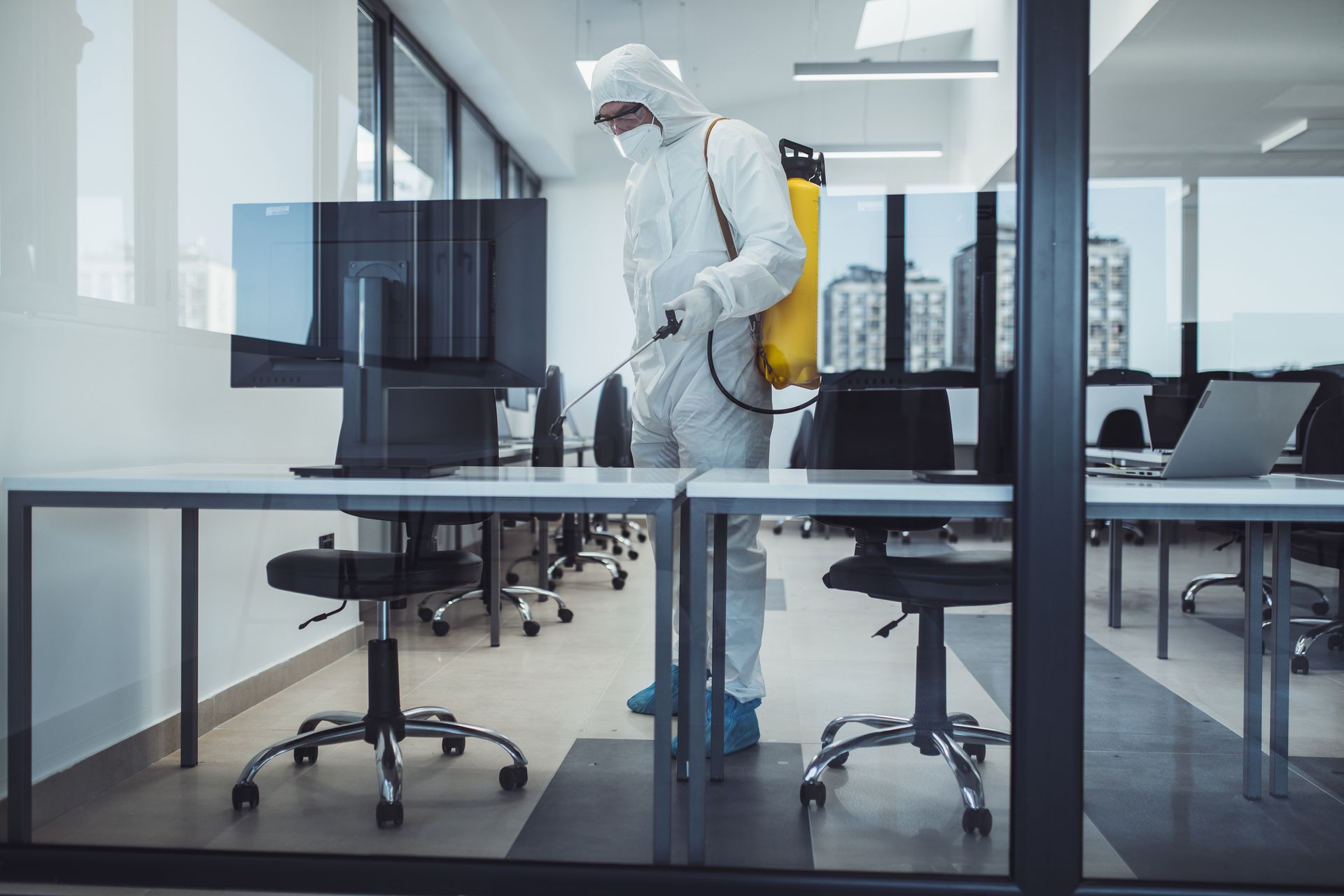 a man in a protective suit is disinfecting an office with a sprayer