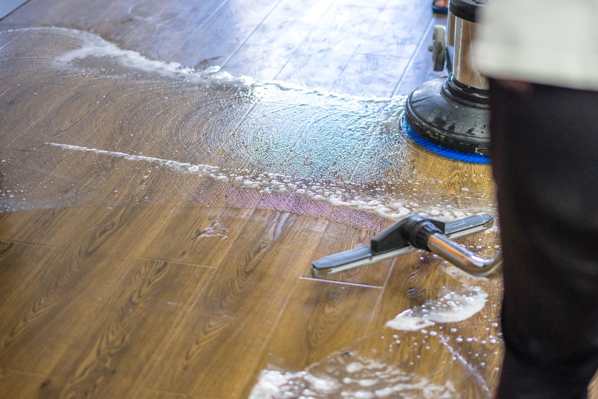 a person is cleaning a wooden floor with a vacuum cleaner