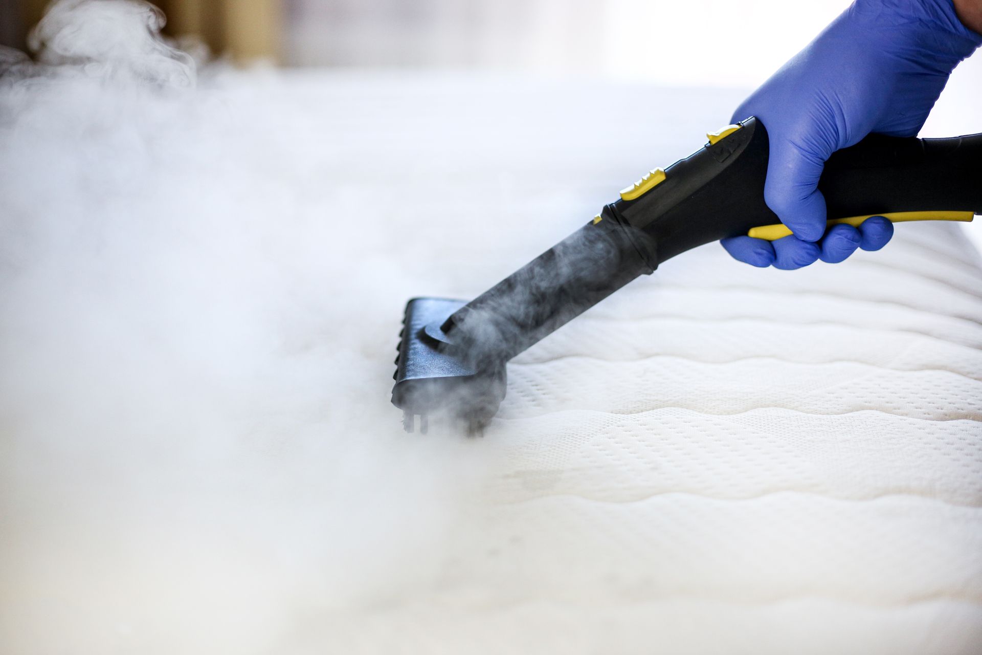 a person is cleaning a mattress with a steam cleaner