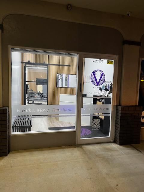 A store front with a glass door and a sign that says V Pilates