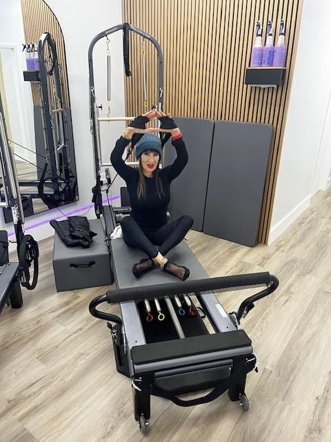 A woman is sitting on a pilates machine in a gym.