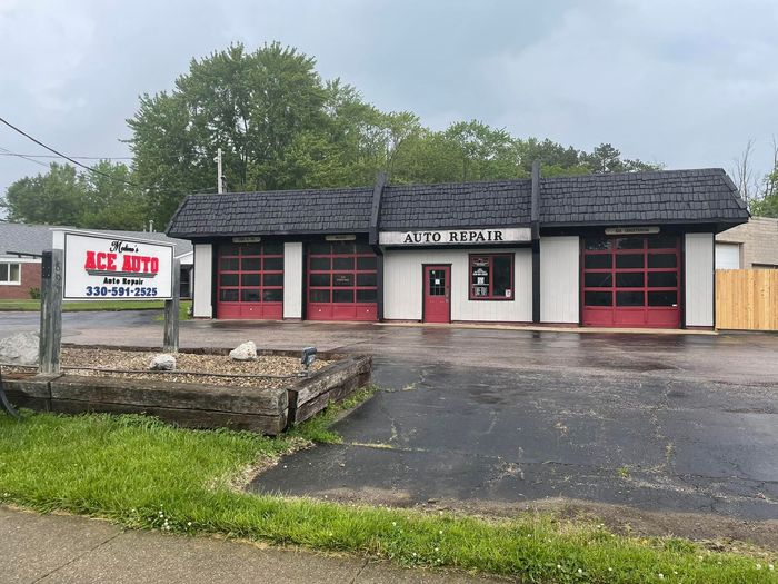 Small rural auto repair shop with red garage doors and a sign reading “Auto Parts” on a cloudy day | Medina’s Ace Auto