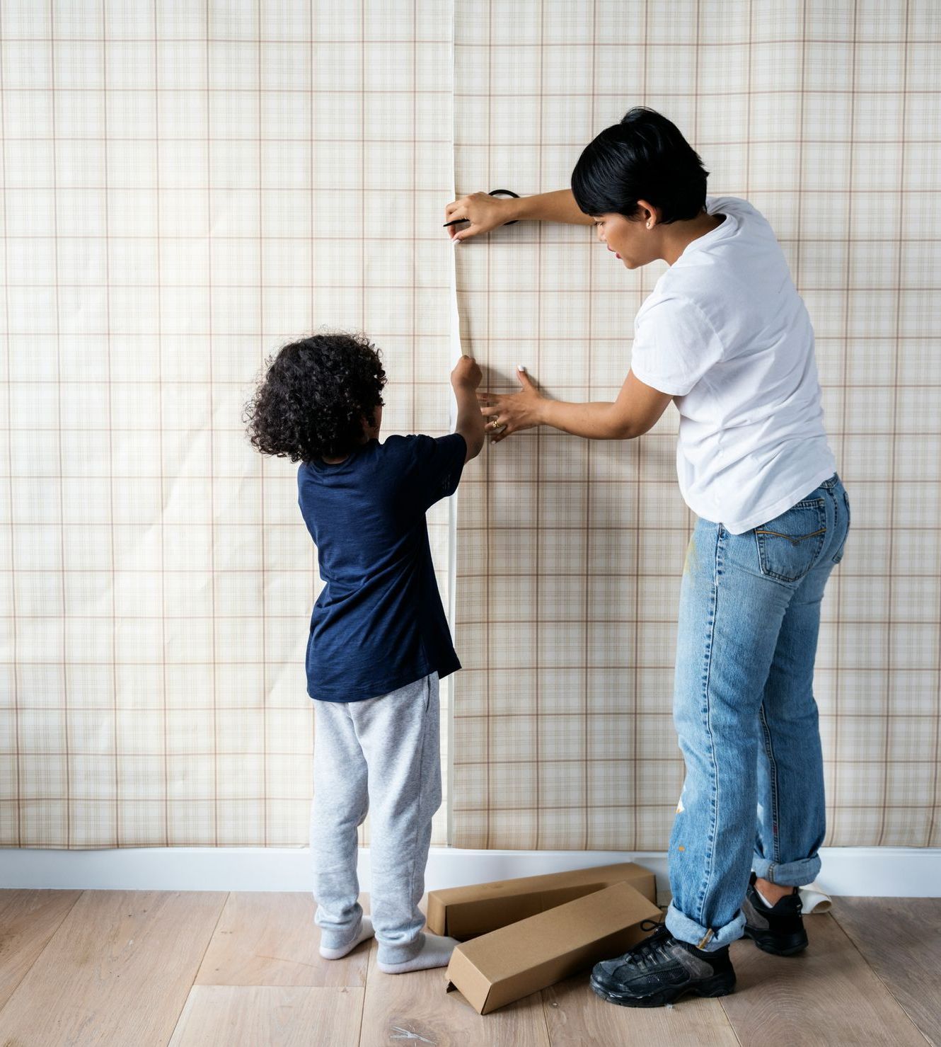 A woman and a child are installing wallpaper on a wall.
