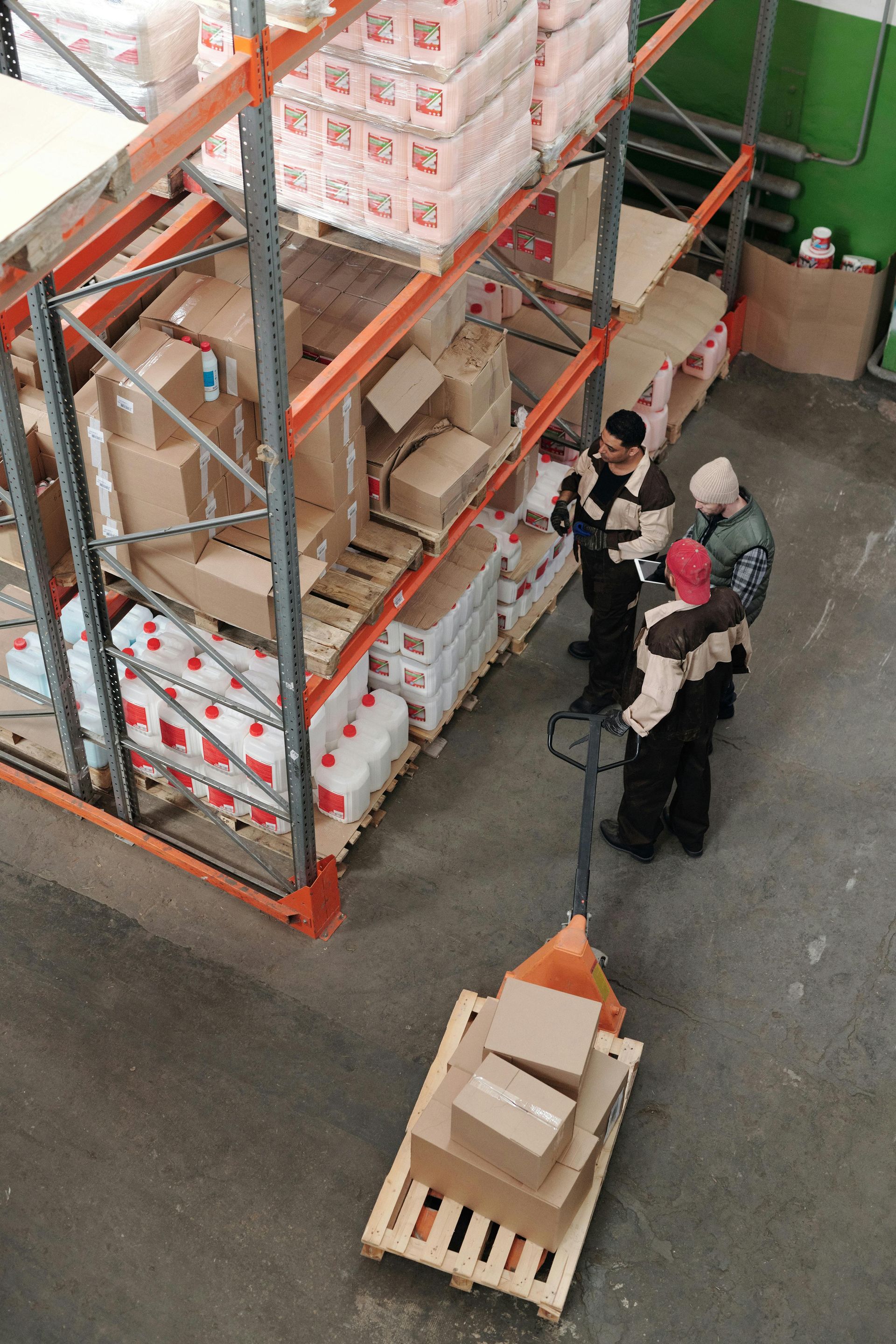 A group of people are standing around a pallet in a warehouse.