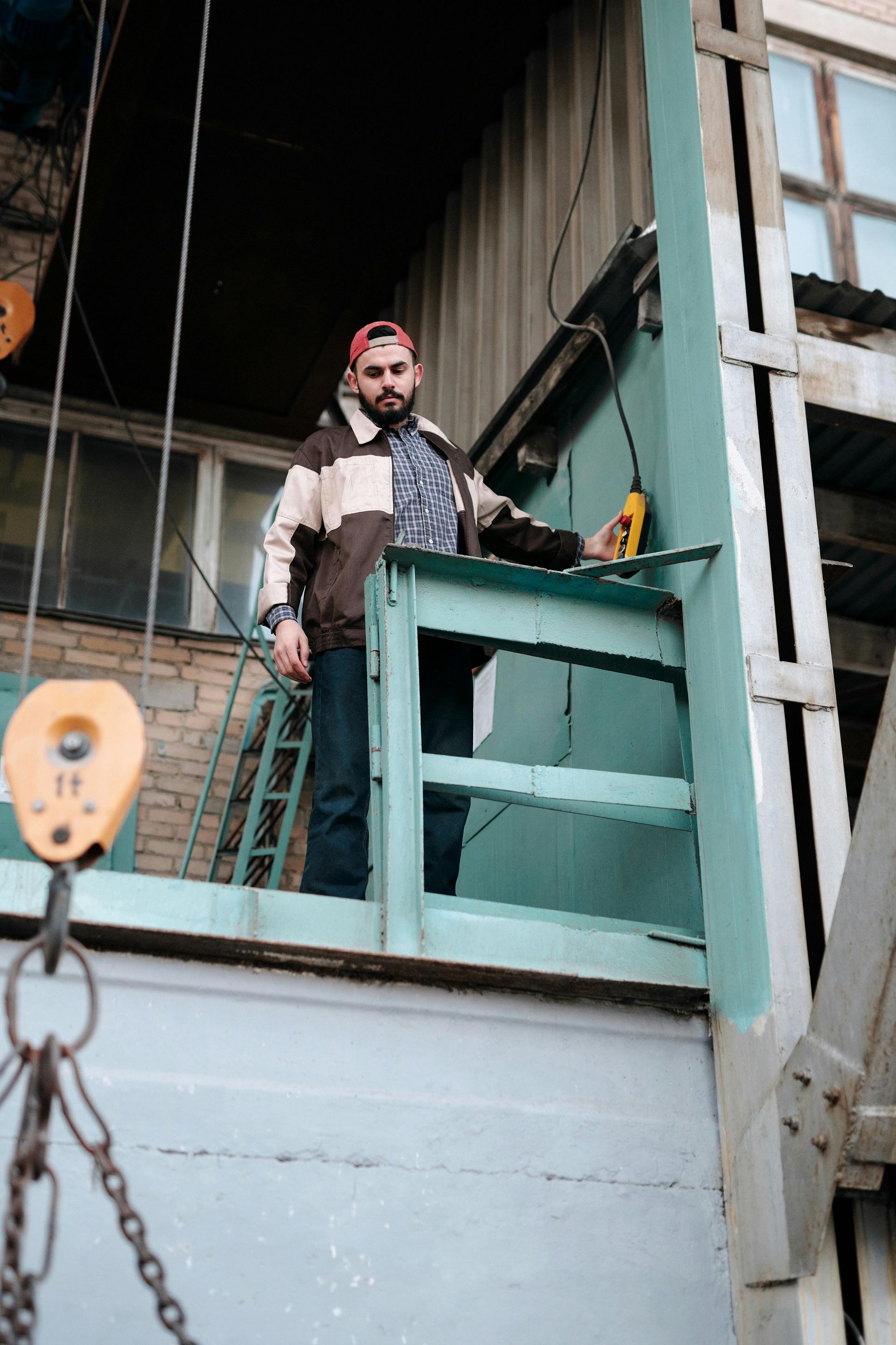 A man is standing on a balcony of a building holding a drill.