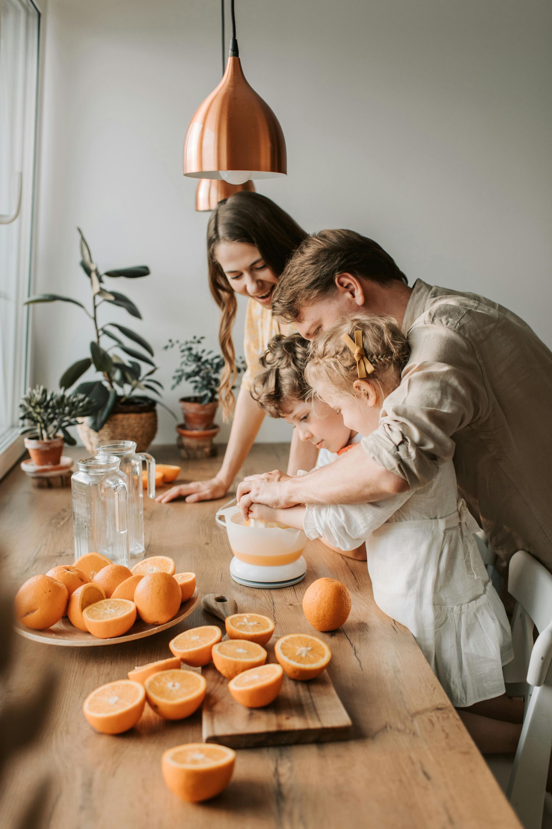 A family is sitting at a table making orange juice.