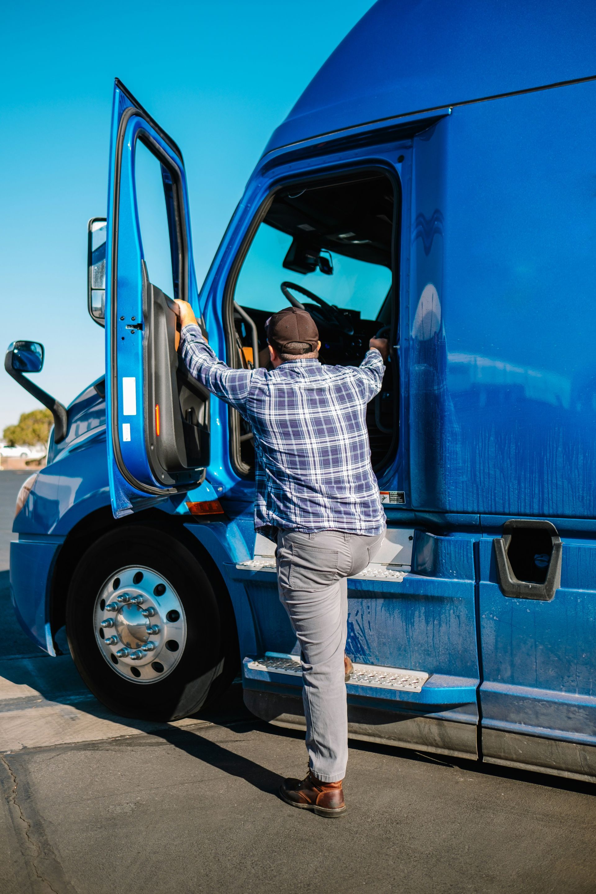 A man is getting out of a blue semi truck.