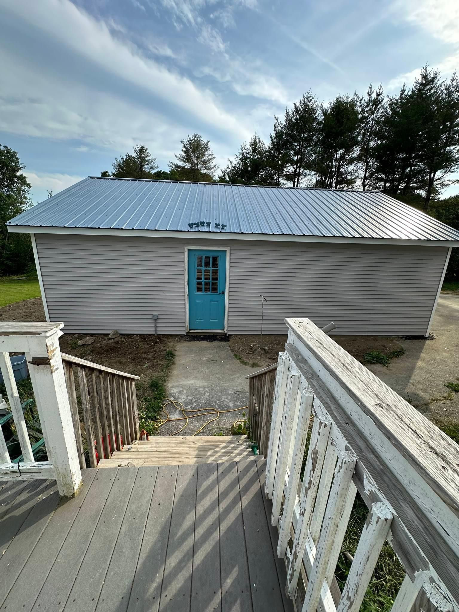 A small white house with a blue door and a metal roof.
