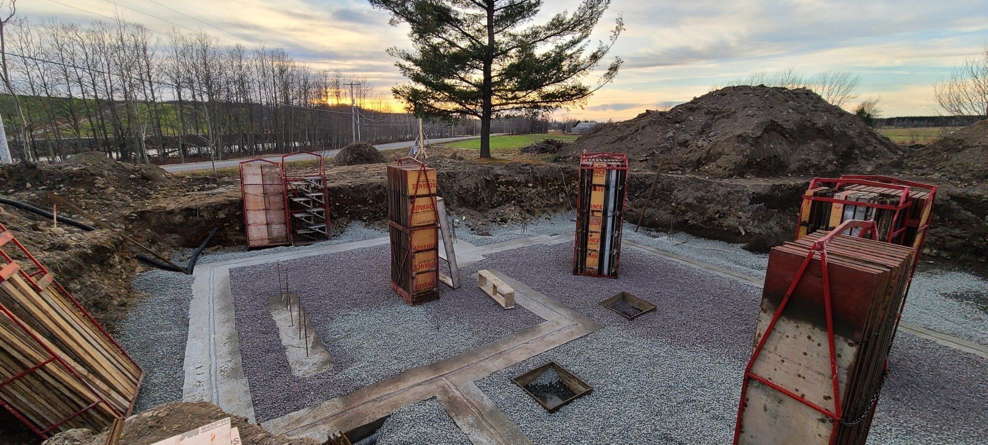 Un chantier de construction avec des piliers en béton et un tas de gravier.