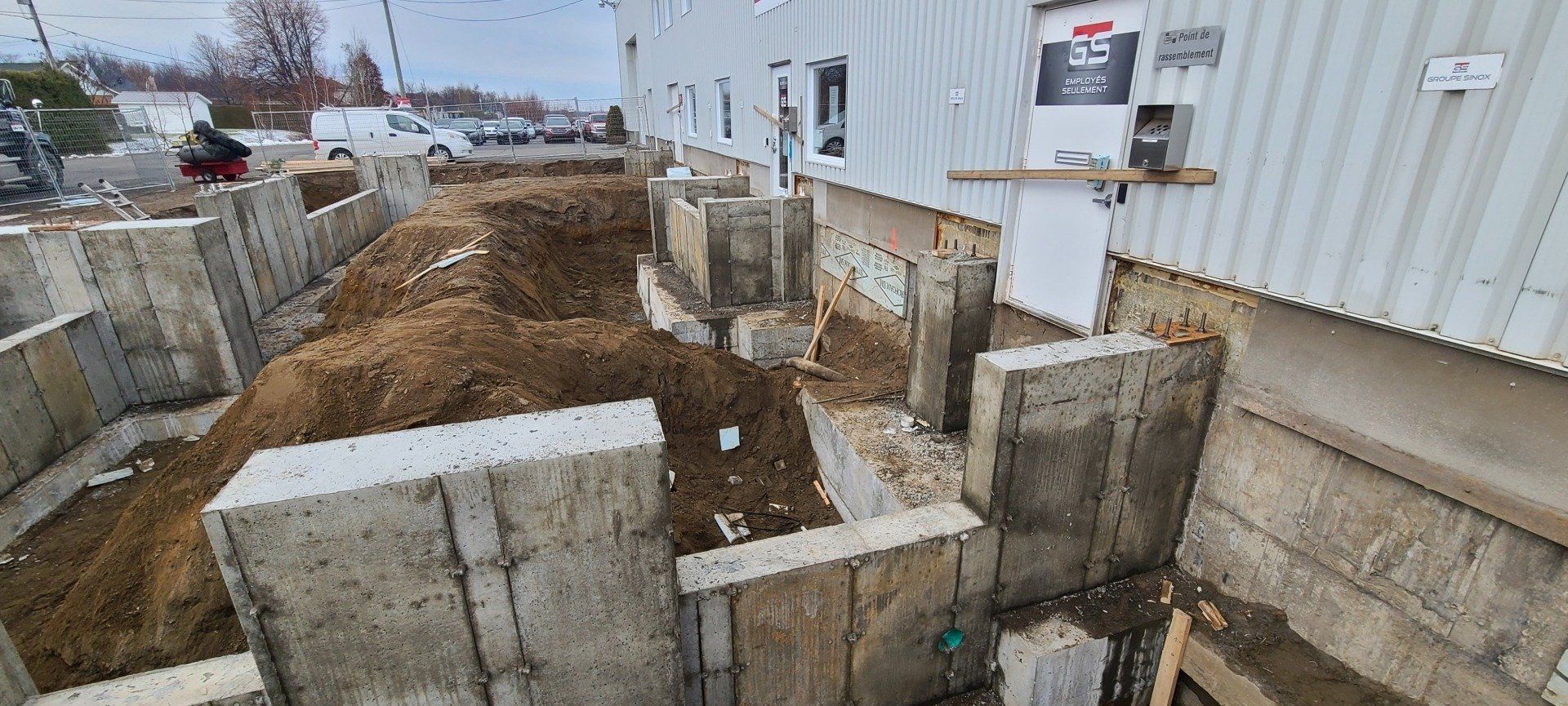 Un mur de béton est en cours de construction devant un bâtiment.