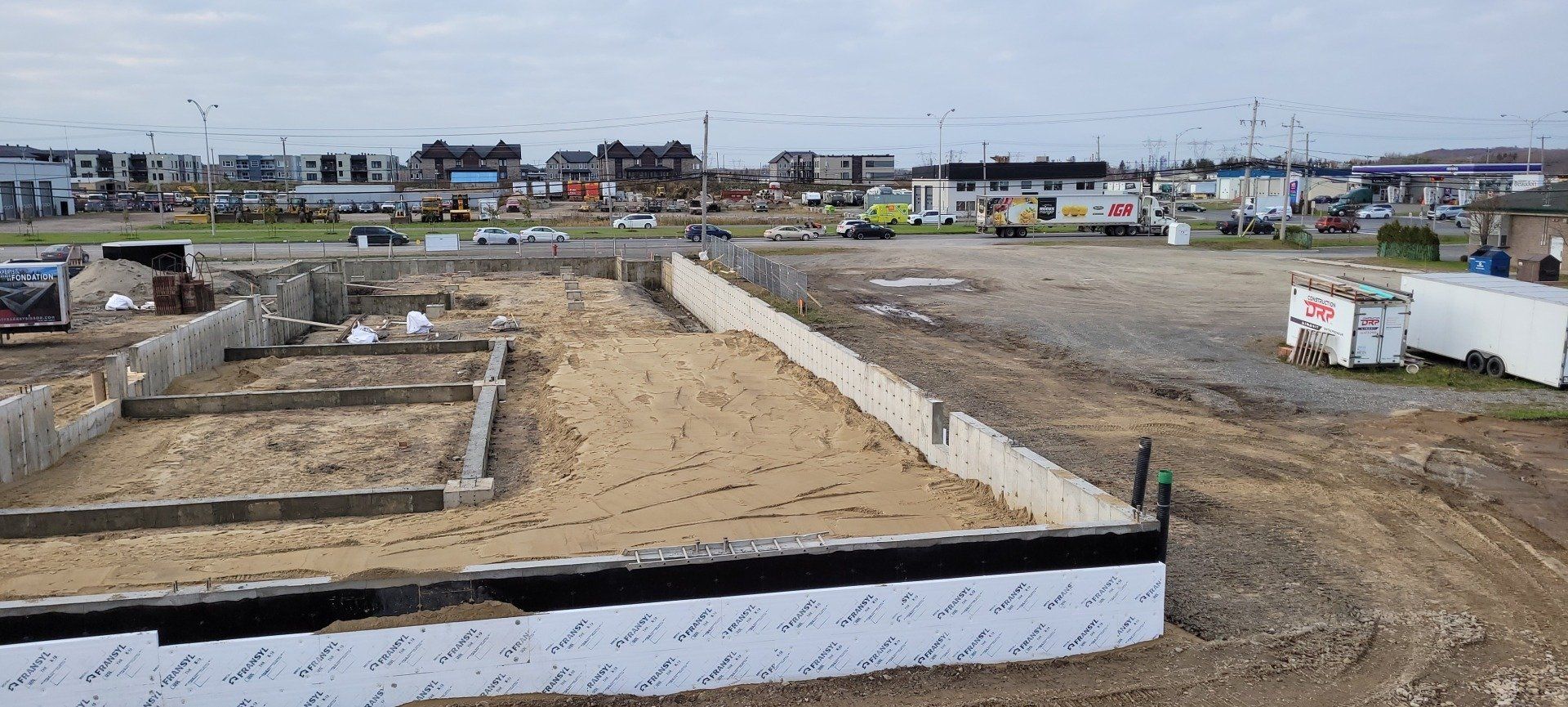Un chantier de construction avec beaucoup de terre et beaucoup de bâtiments en arrière-plan.