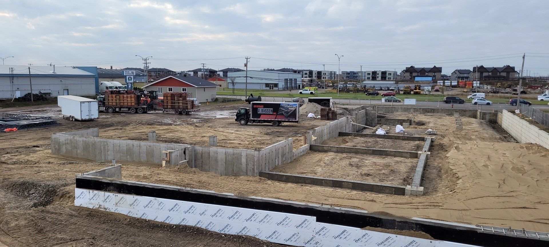 Un chantier de construction avec beaucoup de saleté et des bâtiments en arrière-plan.
