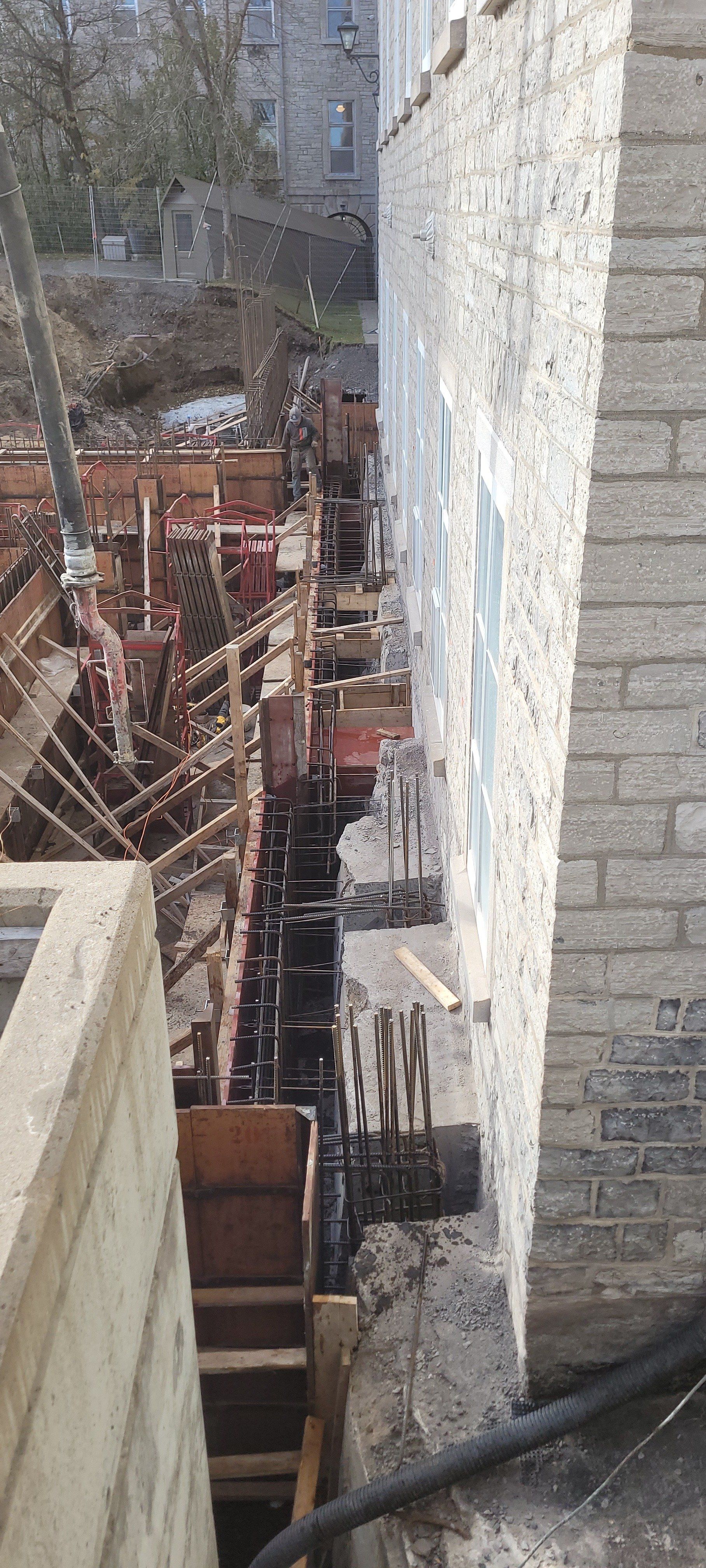 Un mur de briques est en construction à côté d'un bâtiment en construction.