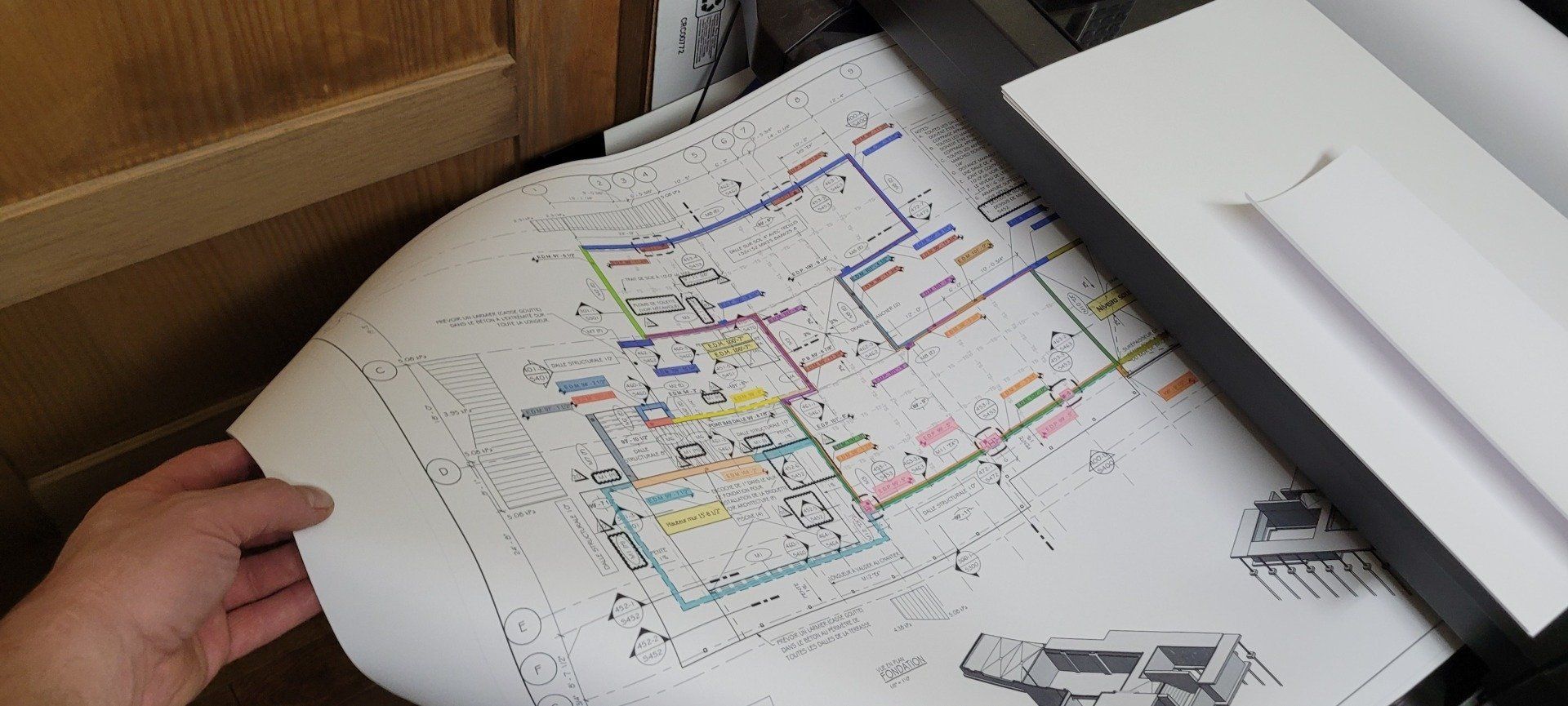 Une personne tient un morceau de papier avec le dessin d'une maison dessus.
