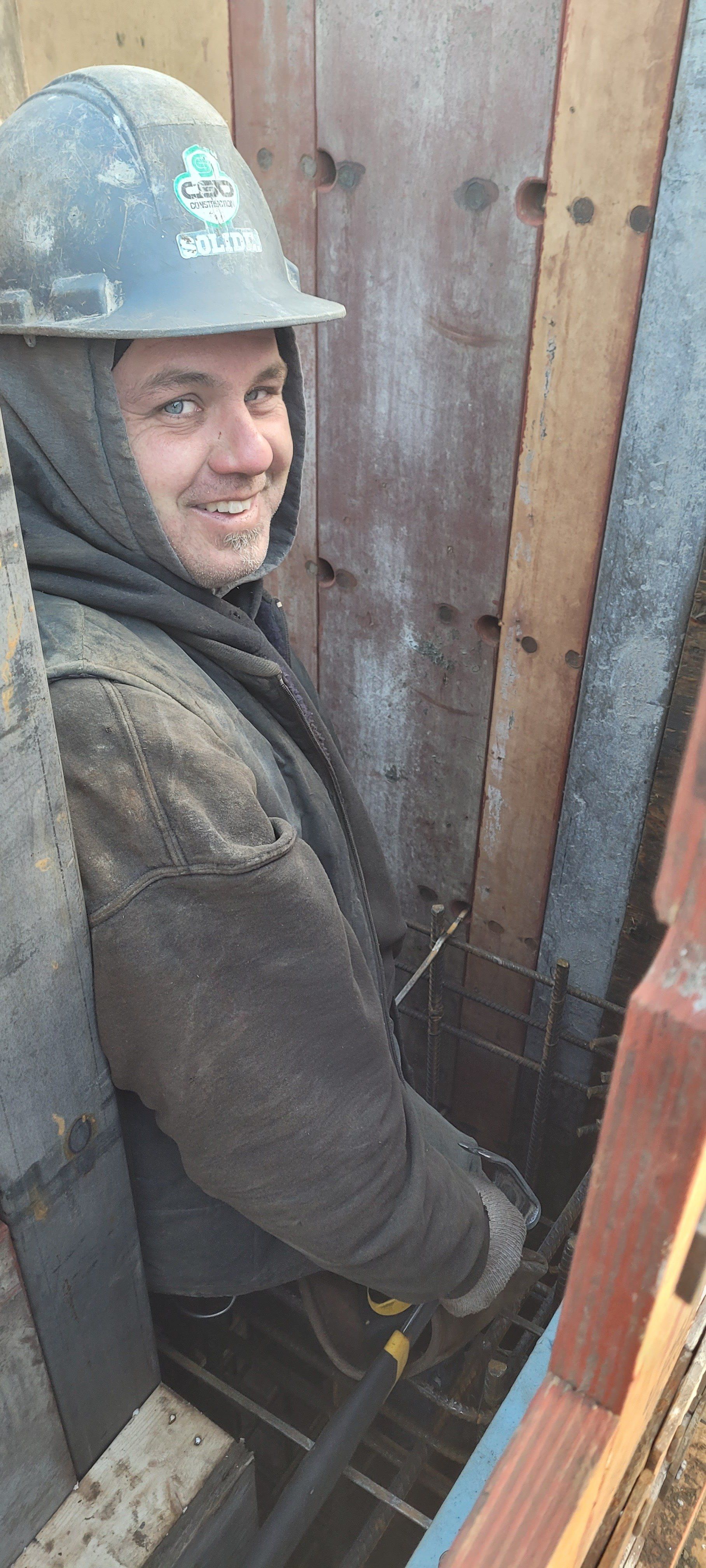 Un homme portant un casque et un sweat à capuche est assis dans un trou.