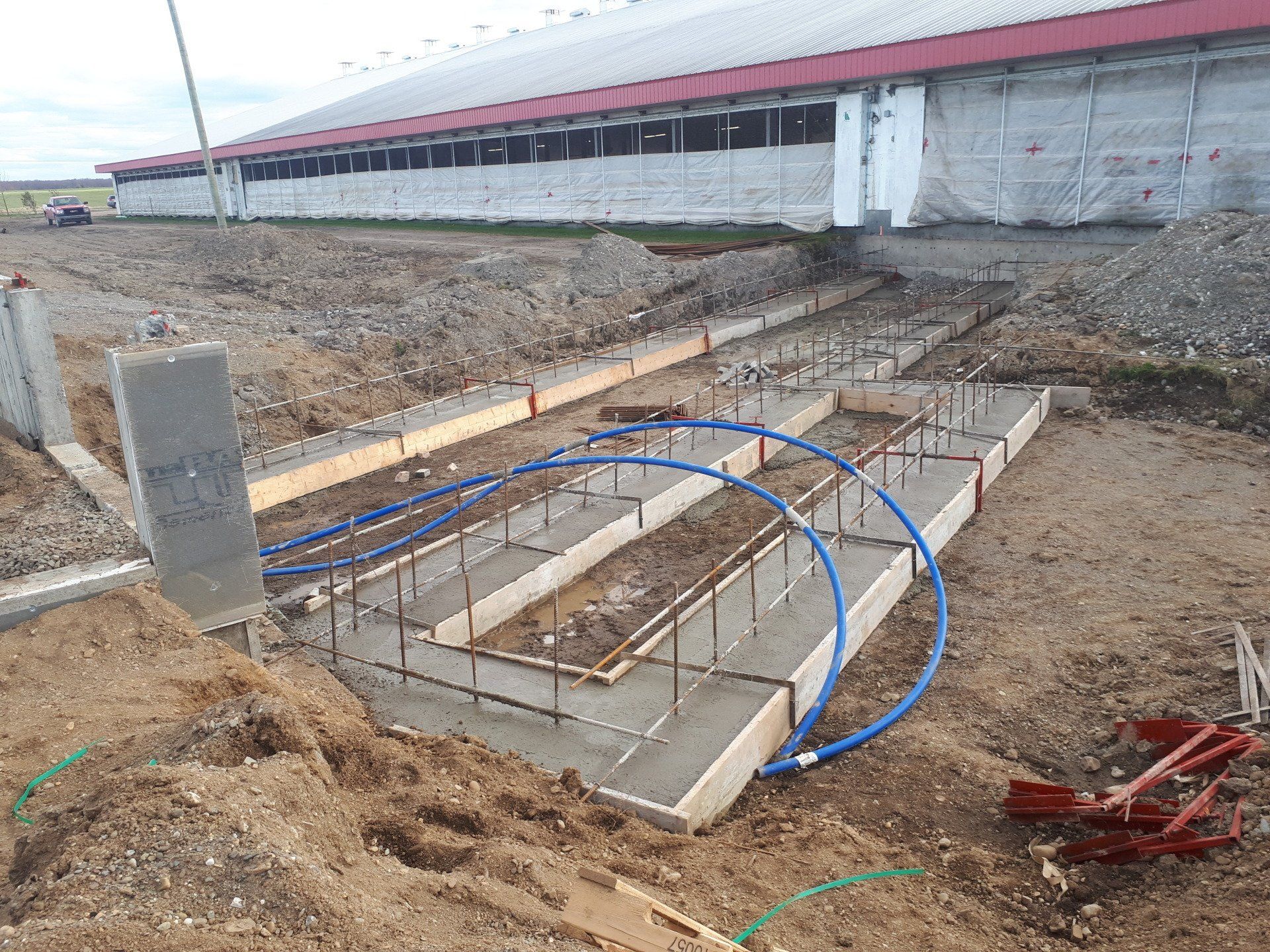 Une fondation en béton est en cours de construction devant un bâtiment.
