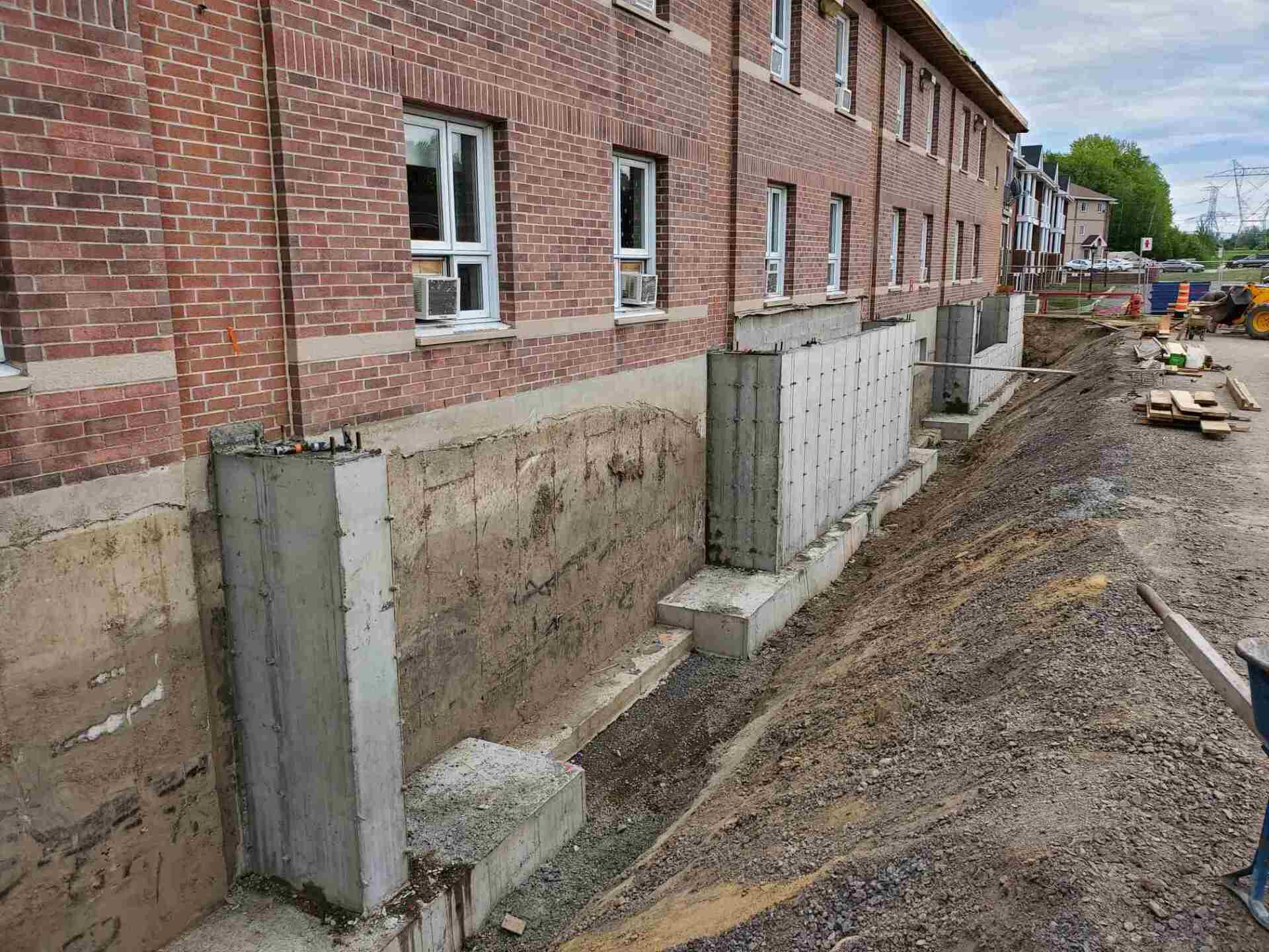 Un bâtiment en brique est en cours de rénovation et un mur en béton est en cours de construction.
