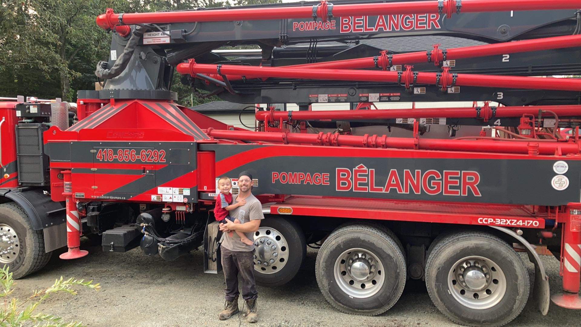 Un homme se tient devant un camion rouge et noir.
