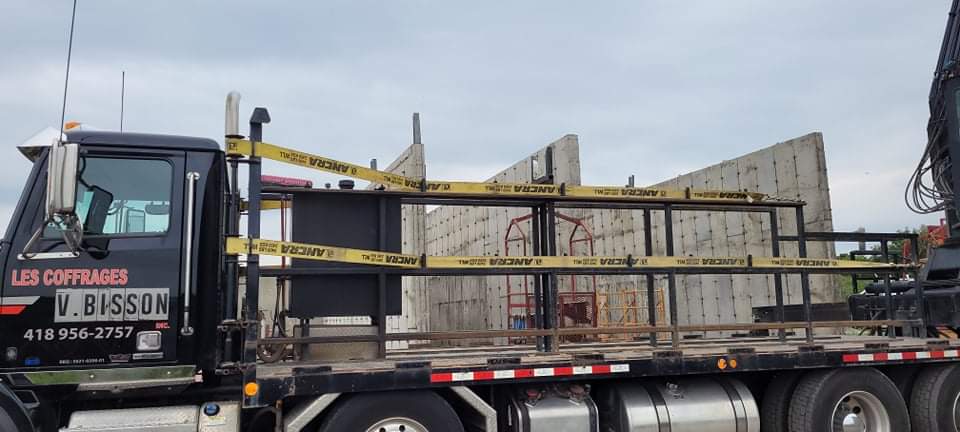 Un camion avec une grue à l'arrière est garé devant un bâtiment en construction.