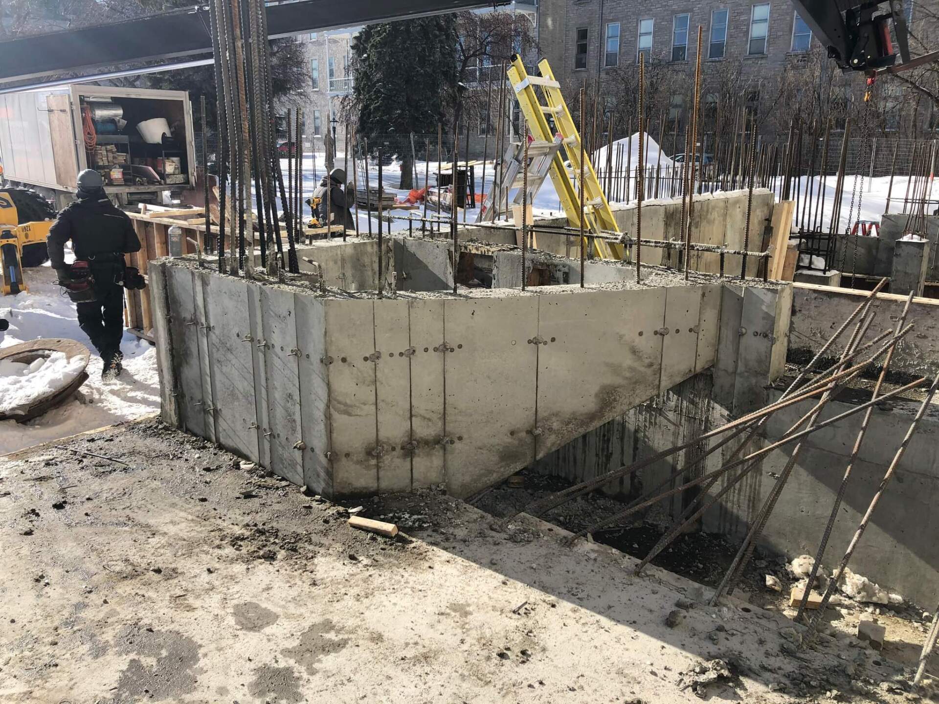 Un homme traverse un chantier de construction avec une échelle jaune.