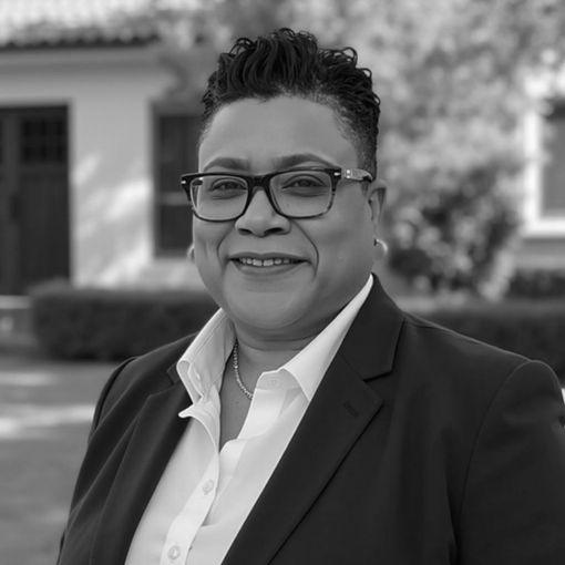 A black and white photo of a woman wearing glasses and a suit.