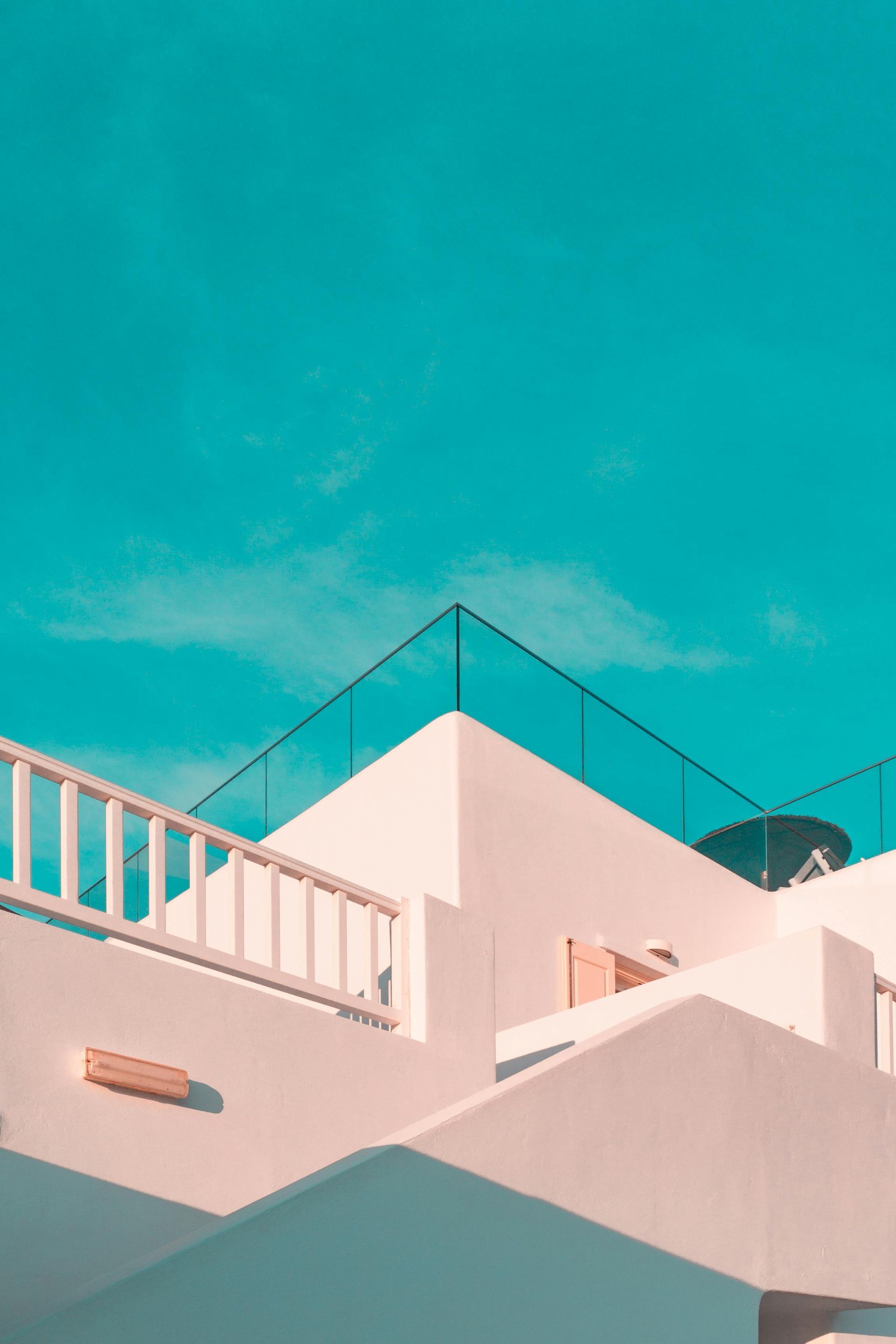 A white building with a balcony and a blue sky in the background.