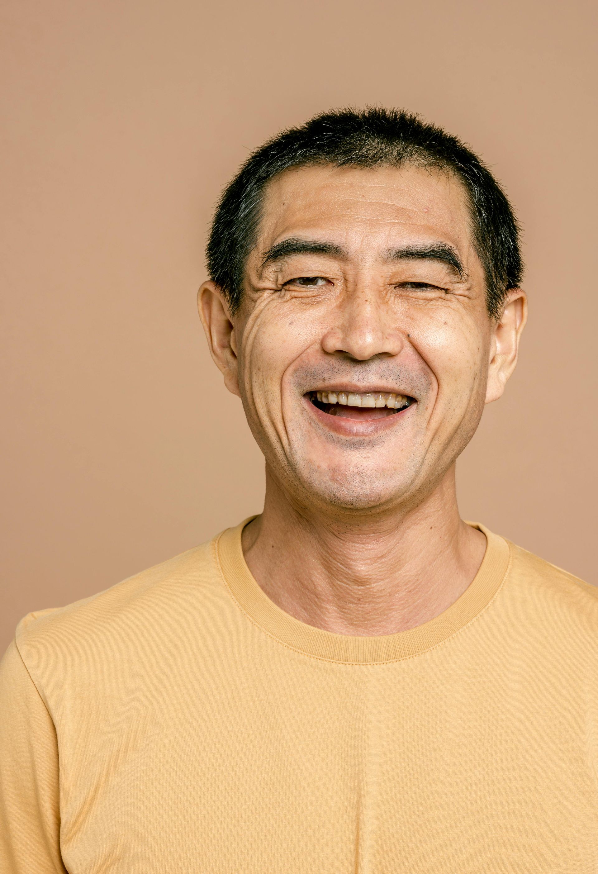 A man in a yellow shirt is smiling and looking at the camera.
