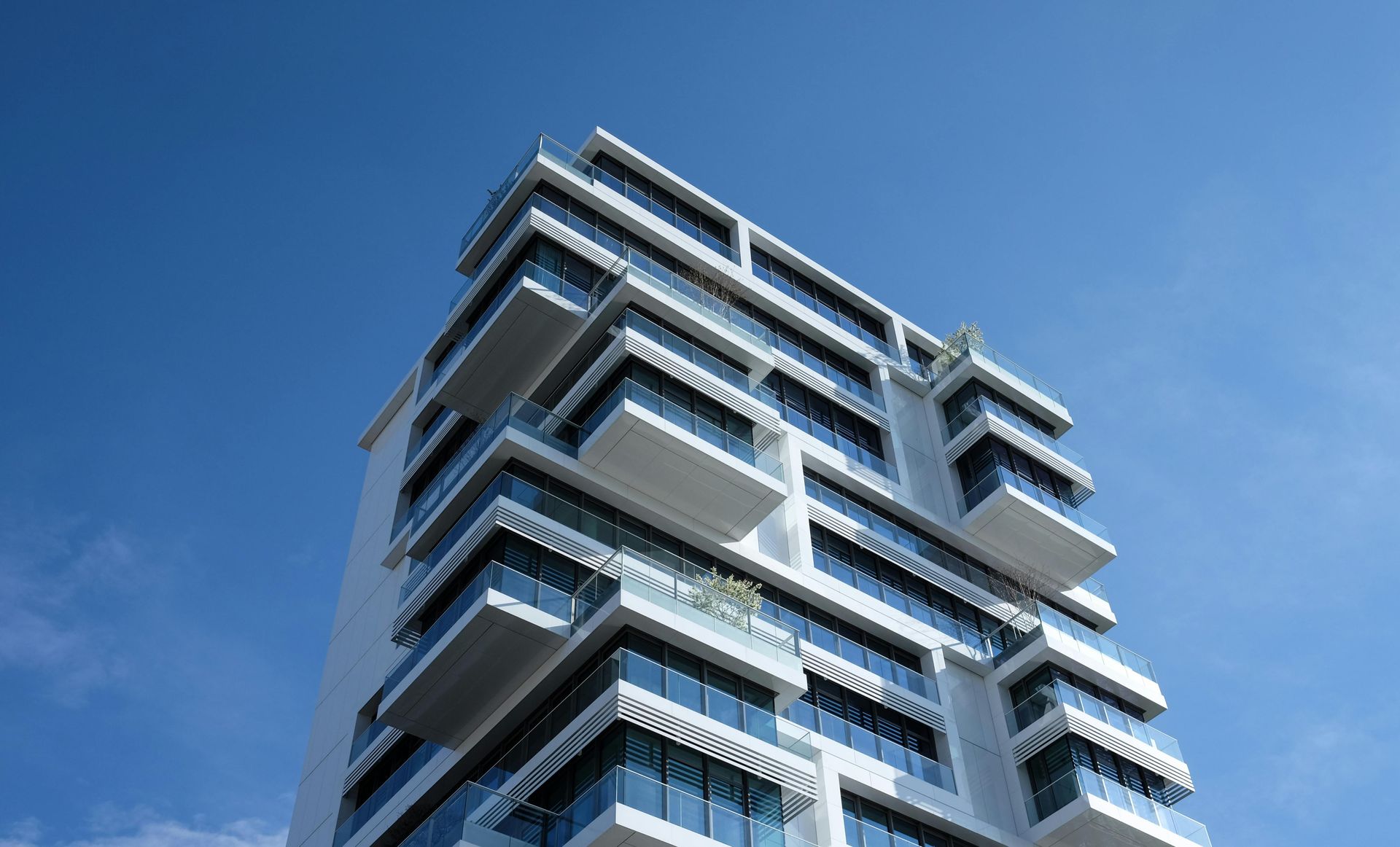 A tall building with a lot of balconies against a blue sky.
