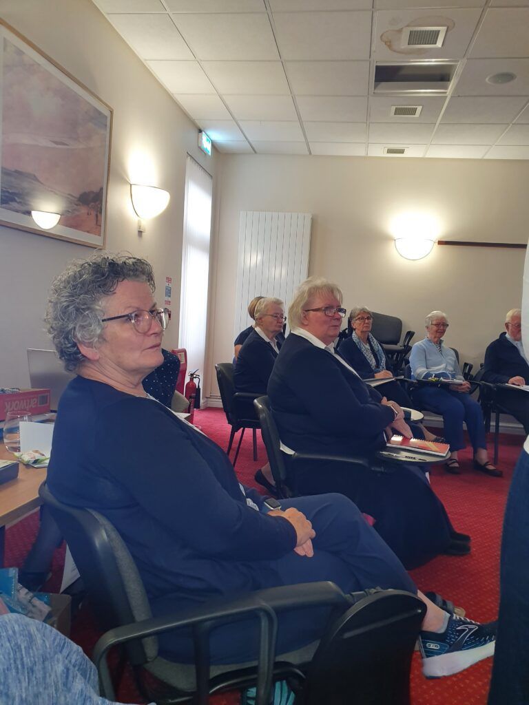 a group of people are sitting in chairs in a room .