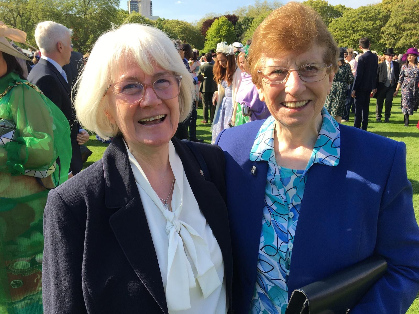 Two older women are posing for a picture in a park.